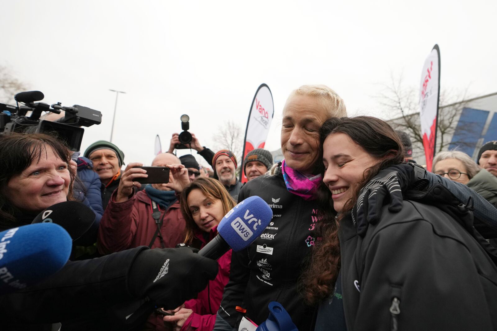 Belgian ultra runner Hilde Dosogne, center, hugs her daughter Lucie after crossing the finish line of her 366th consecutive marathon in Ghent, Belgium, Tuesday, Dec. 31, 2024. (AP Photo/Virginia Mayo)