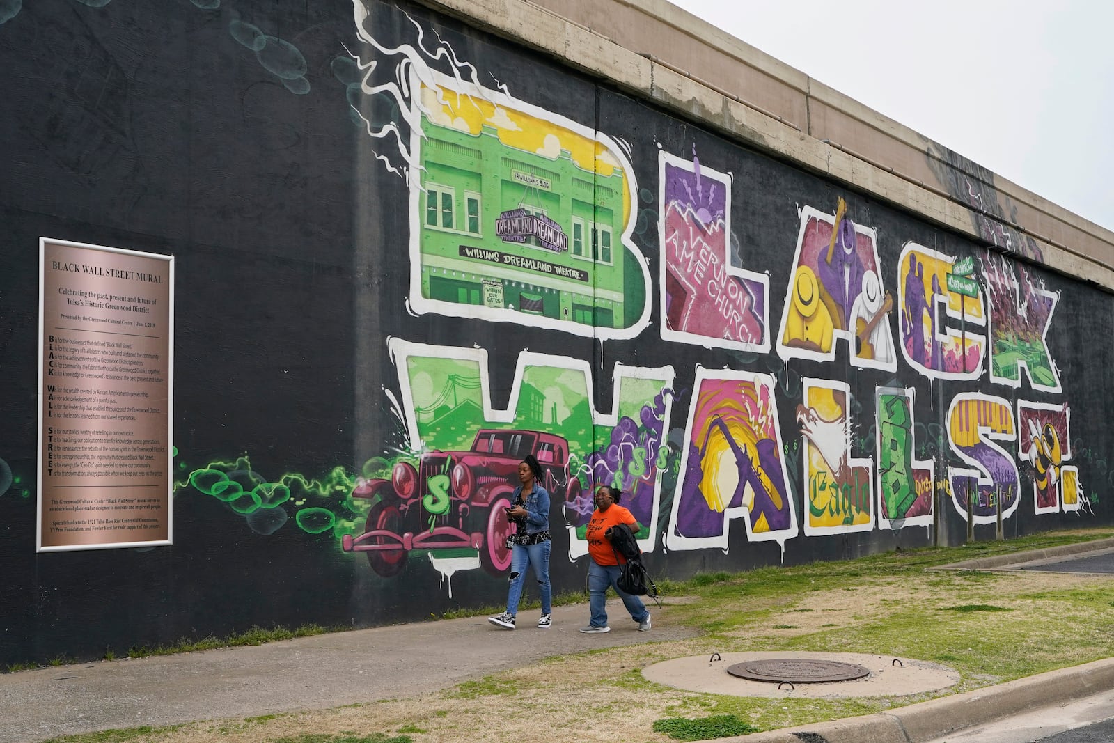 FILE - Javohn Perry, left, of Seattle, and her cousin, Danielle Johnson, right, of Beggs, Okla., walk past a mural commemorating Black Wall Street in Tulsa, Okla., on April 12, 2021. (AP Photo/Sue Ogrocki, File)