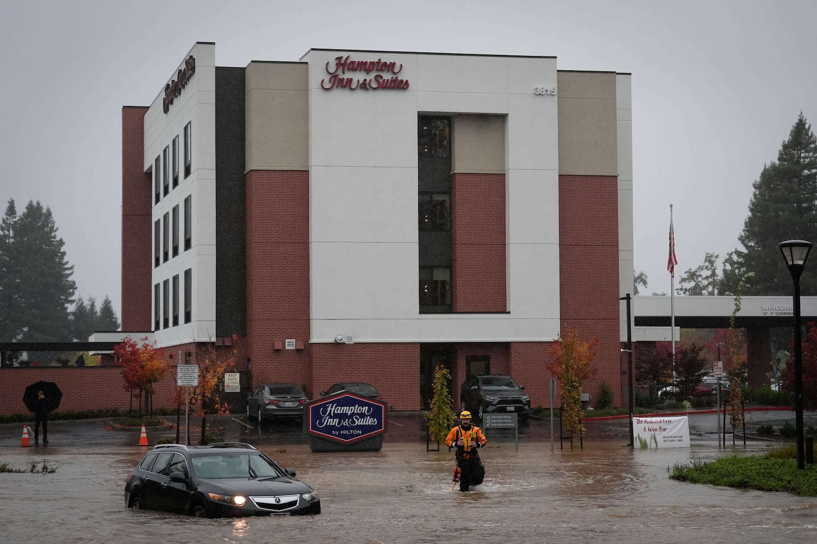 A member of an emergency crew walks in knee-deep flooded street during a storm Thursday, Nov. 21, 2024, in Santa Rosa, Calif. (AP Photo/Jeff Chiu)