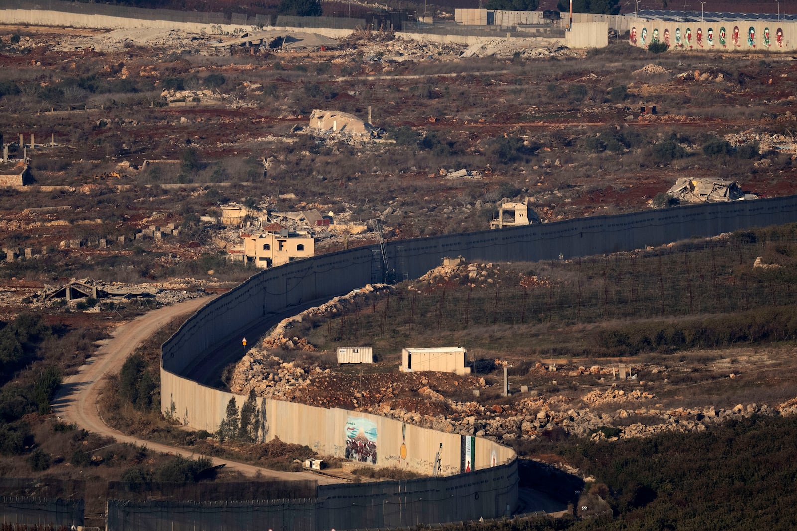 Destroyed buildings in the village of Kfar Kila, southern Lebanon, beside the separation barrier between Israel and Lebanon, are seen from northern Israel, Tuesday, Dec. 3, 2024. (AP Photo/Maya Alleruzzo)