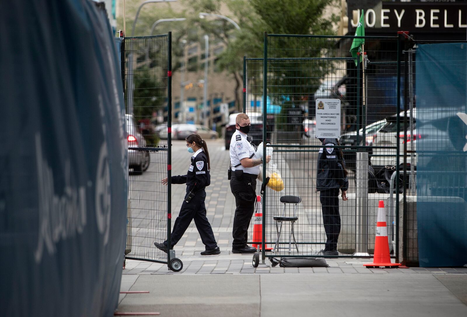 FILE - Security personnel stand at the gate of an entrance to the bubble during the NHL Western Conference Stanley Cup hockey playoffs in Edmonton, Alberta, Monday, Aug. 24, 2020. When the NHL made plans to resume its season for the playoffs in two quarantined bubbles, it added the leap of consolidating to one for the conference finals and Stanley Cup Final. Two Eastern Conference teams and league staff made their way from Toronto to Edmonton with no hiccups, and Deputy Commissioner Bill Daly said it wasn’t as daunting as expected. (Jason Franson/The Canadian Press via AP, File)