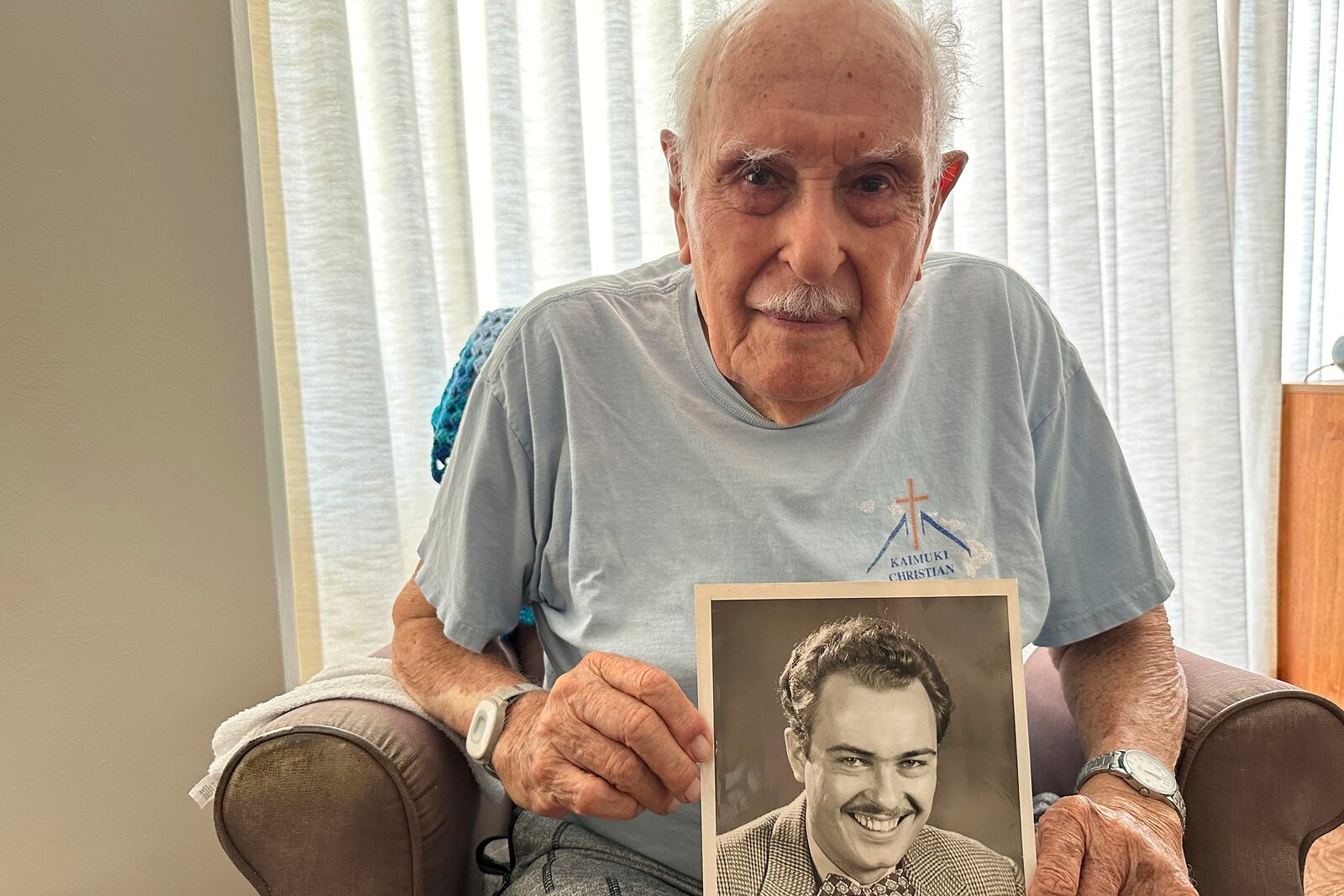 Jim Becker, a former Associated Press journalist, holds a photo album showing a 1947 photo of him as an AP reporter, at his home in Kaneohe, Hawaii, May 21, 2024. (AP Photo/Audrey McAvoy)