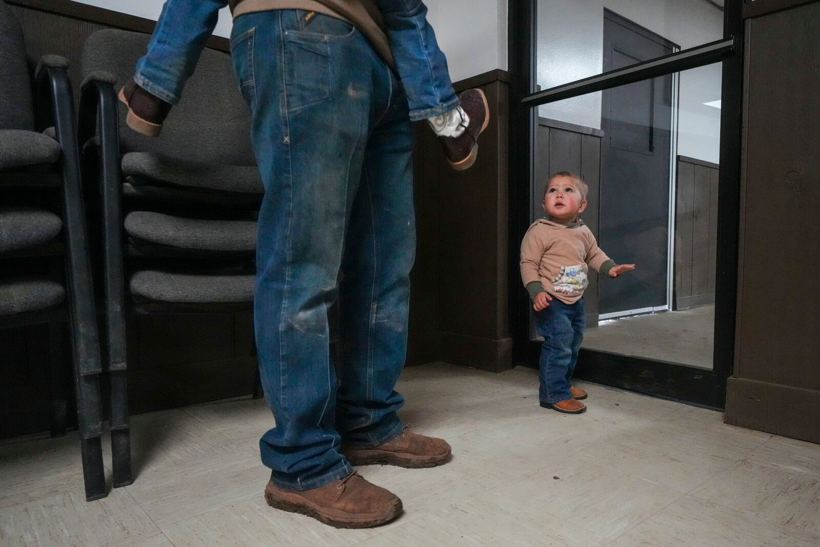 Sterling Duke, 1, of Lexington, Okla., looks toward his dad Garrison Duke, a cattle seller, carrying Pecos Duke, 3, near the auction arena at the Oklahoma National Stockyards Tuesday, Jan. 14, 2025, in Oklahoma City. (AP Photo/Julio Cortez)