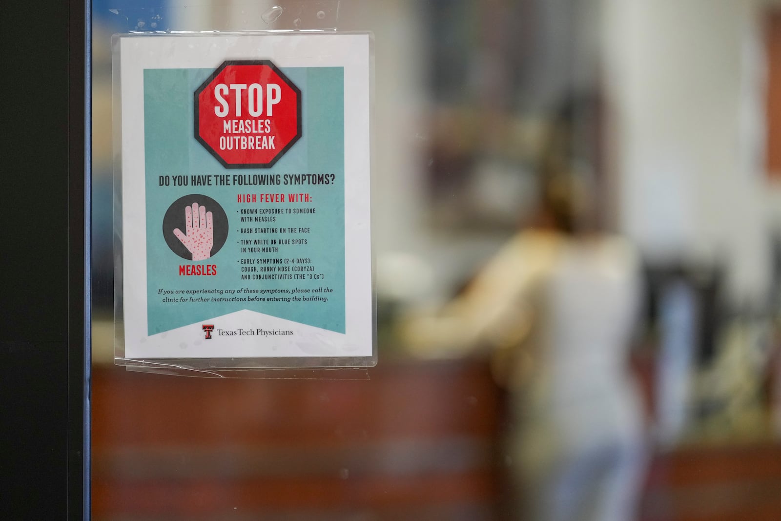 A sign warning of measles is posted on a glass door as a patient checks in for an appointment in the family medicine wing of at the Texas Tech Physicians of the Permian Basin Monday, Feb. 24, 2025, in Odessa, Texas. (AP Photo/Julio Cortez)