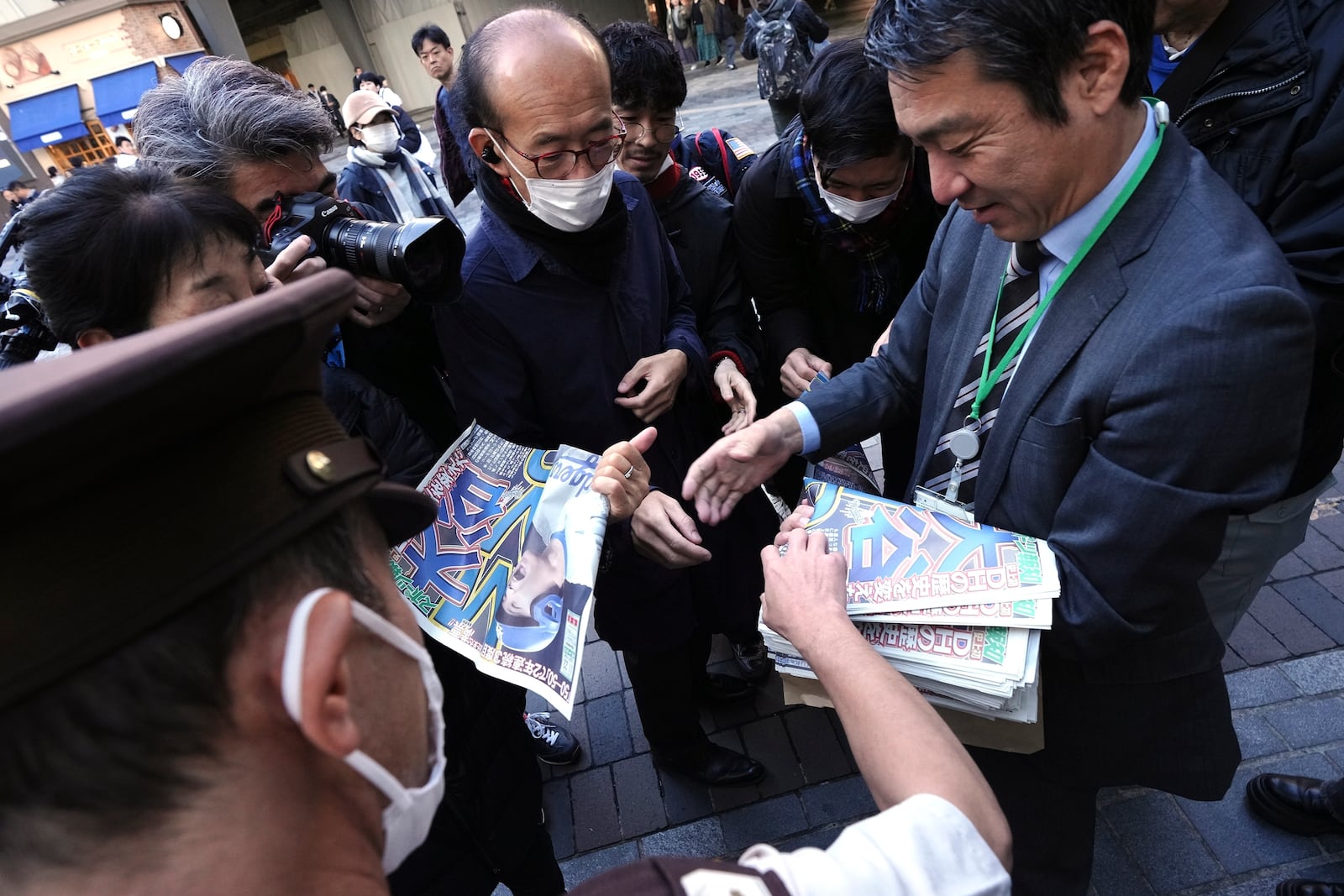 A staff member distributes an extra edition of the Sports Hochi newspaper reporting that Los Angeles Dodgers' Shohei Ohtani won his third Most Valuable Player award, Friday, Nov. 22, 2024, in Tokyo. (AP Photo/Eugene Hoshiko)