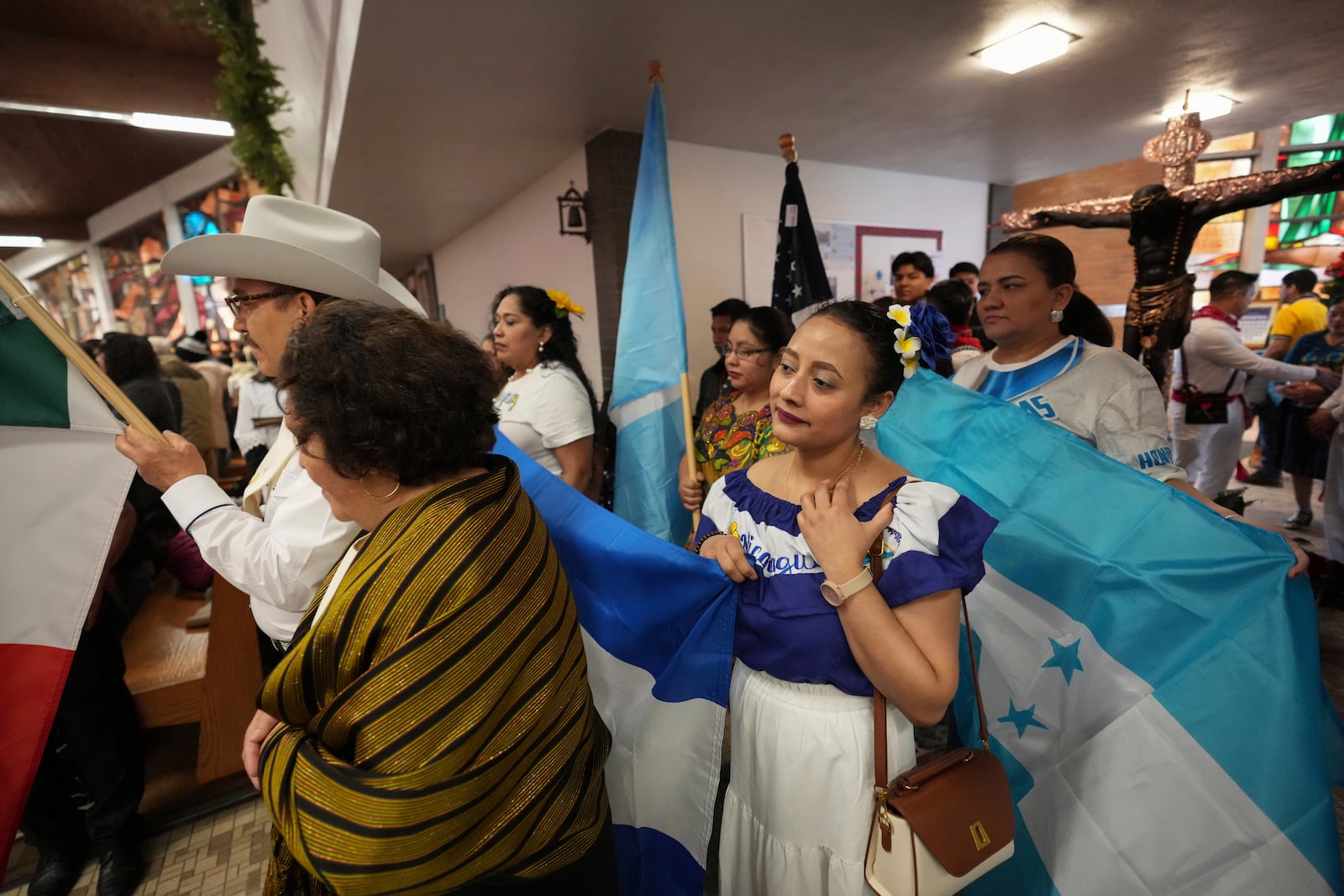 A woman wearing a dress that reads "Nicaragua" waits at St. Mary's Catholic Church to dance at a celebration of the feast day of Guatemala's Black Christ of Esquipulas in Worthington, Minnesota, Sunday, Jan. 12, 2025. (AP Photo/Abbie Parr)