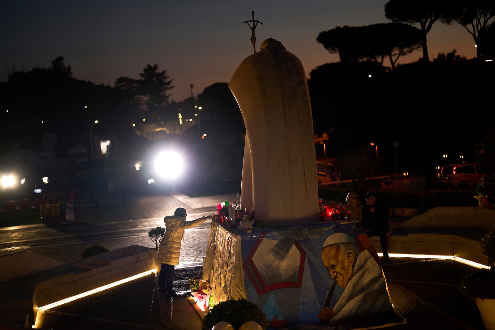 A woman touches the statue of Pope John Paul II placed outside the Agostino Gemelli hospital in Rome, Thursday, March 6, 2025. (AP Photo/Francisco Seco)