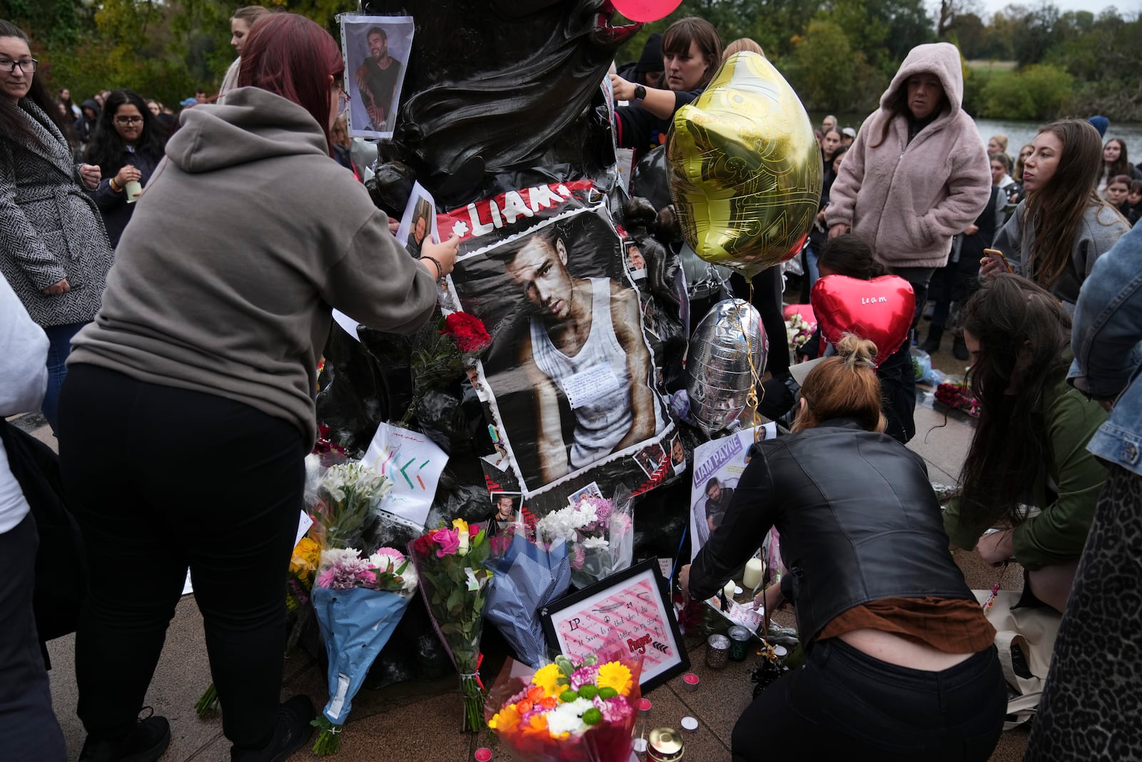 Fans gather near the Peter Pan statue in Hyde Park, London to pay tribute to late British singer Liam Payne, former member of the British pop band One Direction, Sunday, Oct. 20, 2024. (Photo by Scott A Garfitt/Invision/AP)