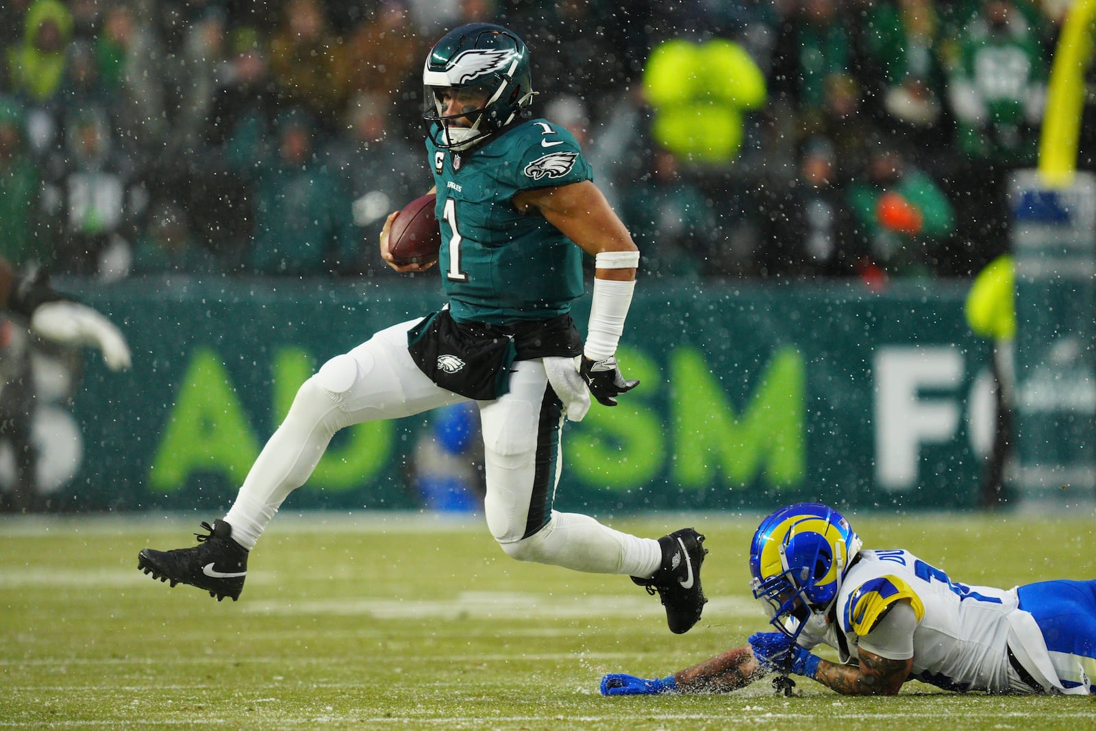 Philadelphia Eagles quarterback Jalen Hurts (1) runs with the ball past Los Angeles Rams cornerback Cobie Durant (14) during the first half of an NFL football NFC divisional playoff game Sunday, Jan. 19, 2025, in Philadelphia. (AP Photo/Derik Hamilton)