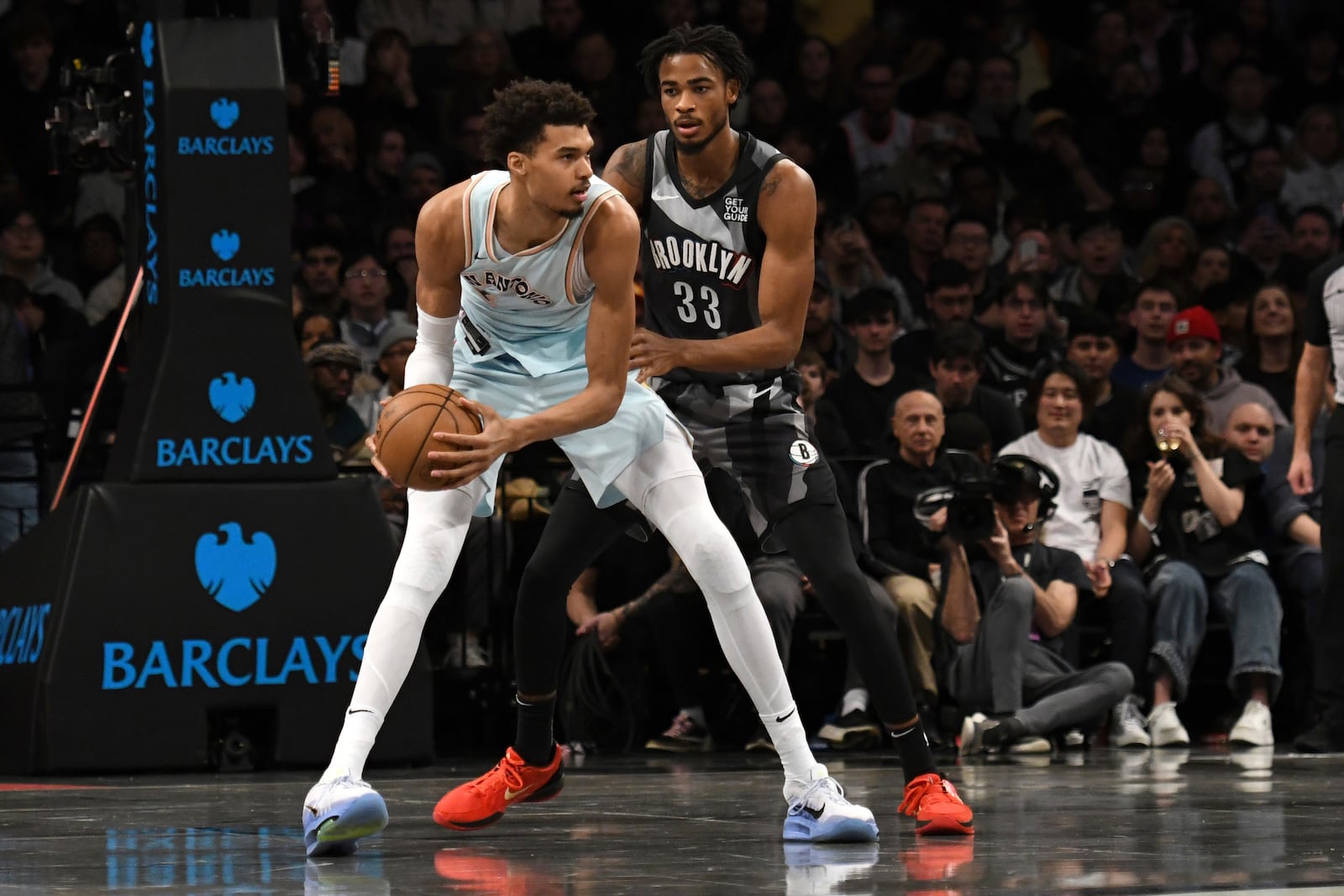 San Antonio Spurs' Victor Wembanyama, left, defends the ball from Brooklyn Nets' Nic Claxton, right, during the first half of an NBA basketball game Friday, Dec. 27, 2024, in New York. (AP Photo/Pamela Smith)