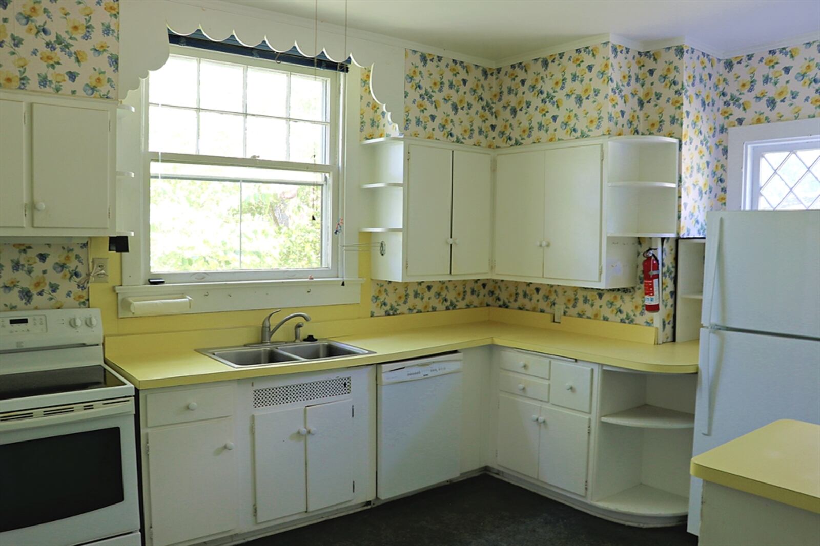 In the kitchen, white cabinets with yellow counters fill nearly all the wall space and surround the appliances, including a range, dishwasher and two refrigerator nooks. 