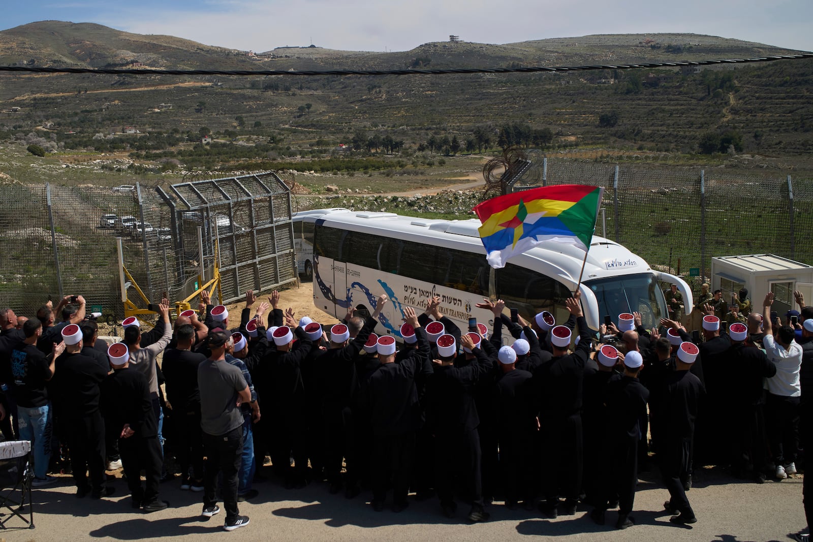 Buses carrying members of the Syrian Druze community are welcomed by Druze clerics at the border with Syria, as they enter into the village of Majdal Shams, in the Israeli-controlled Golan Heights, Friday, March 14, 2025. (AP Photo/Leo Correa)