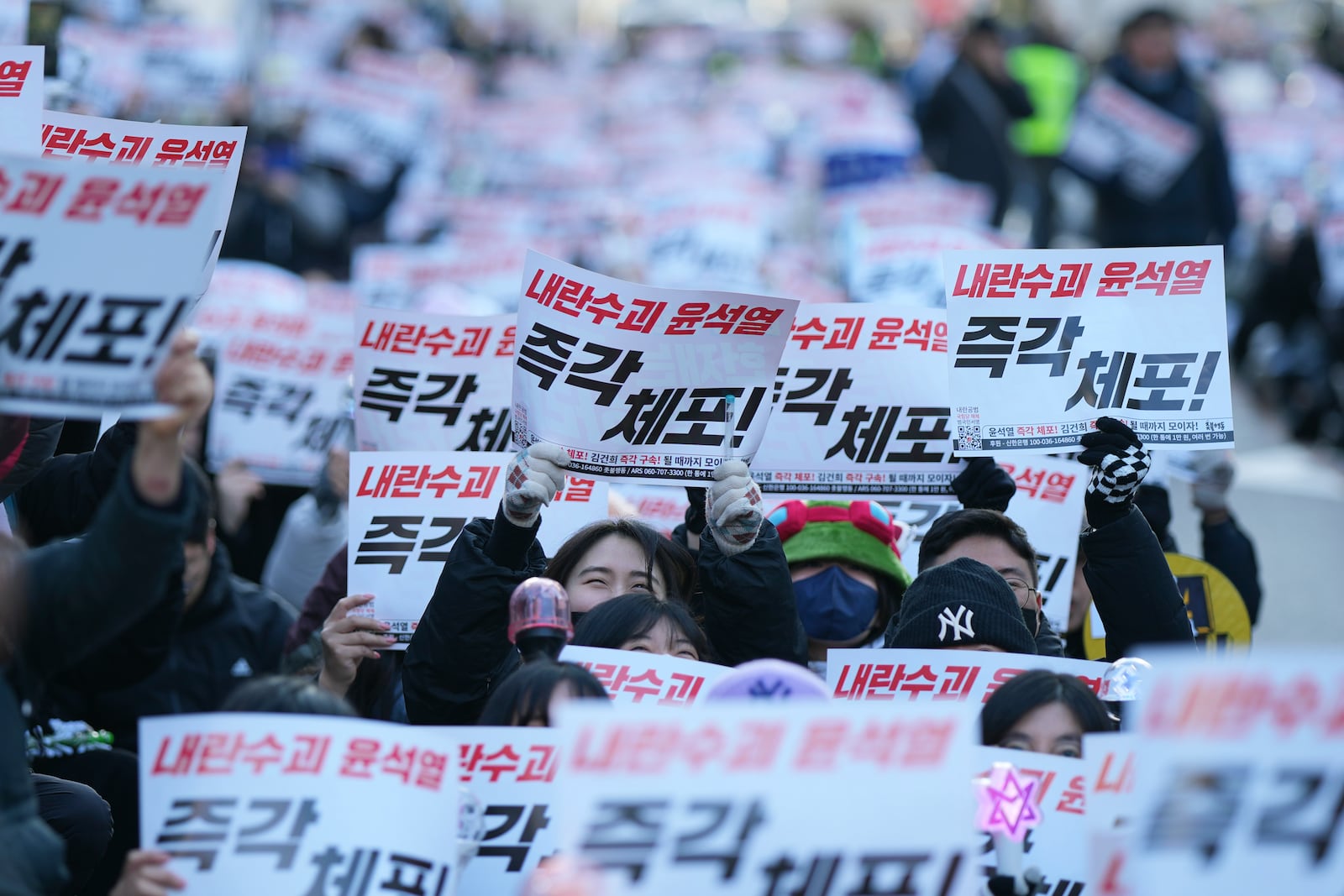 Participants shout slogans during a rally calling on the Constitutional Court to dismiss the President Yoon Suk Yeol, in Seoul, South Korea, Sunday, Dec. 15, 2024. The signs read "Immediately arrest." (AP Photo/Lee Jin-man)