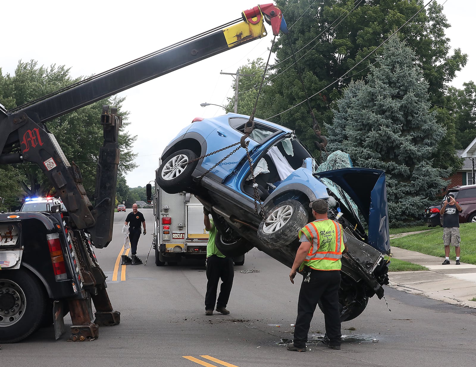 A towing crew lifts a car back onto Balsam Drive after a crash. BILL LACKEY/STAFF