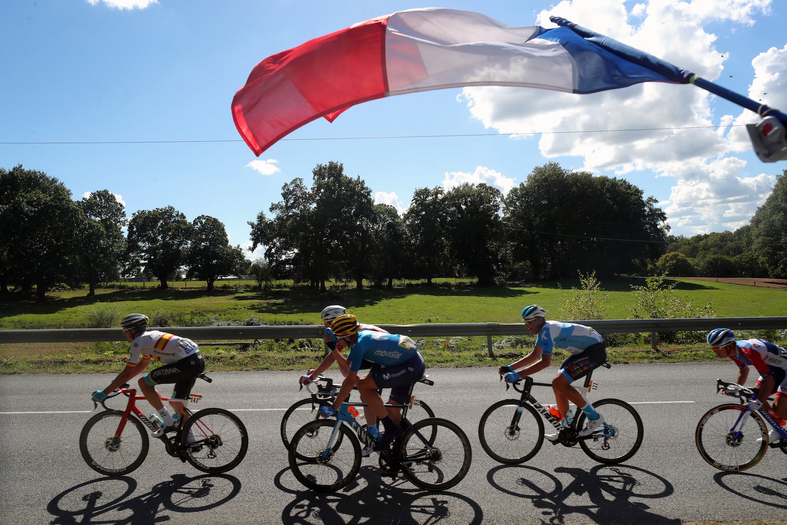 A French flag flies over riders in a breakeway during the stage 12 of the Tour de France cycling race over 218 kilometers from Chauvigny to Sarran, Thursday, Sept. 10, 2020. (AP Photo/Thibault Camus)