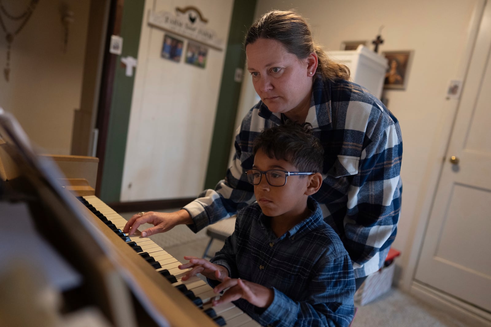 Erin Young helps her adopted son Lucas, 8, with a song on the piano during homeschooling on Tuesday, Nov. 12, 2024, in Sunbury, Ohio. (AP Photo/Carolyn Kaster)