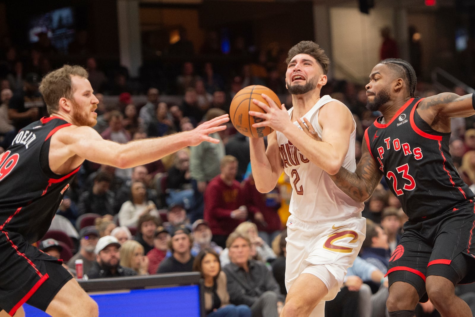 Cleveland Cavaliers' Ty Jerome (2) drives to the basket between Toronto Raptors' Jakob Poeltl, left, and Jamal Shead (23) during the second half of an NBA basketball game in Cleveland, Sunday, Nov 24, 2024. (AP Photo/Phil Long)