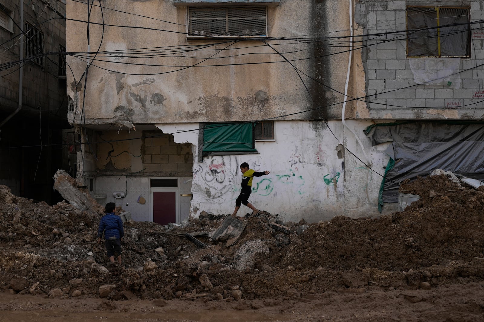 A boy walks along of a damaged street after the latest Israeli military operation, in the West Bank city of Tulkarem, Thursday, Dec. 26, 2024. (AP Photo/Matias Delacroix)