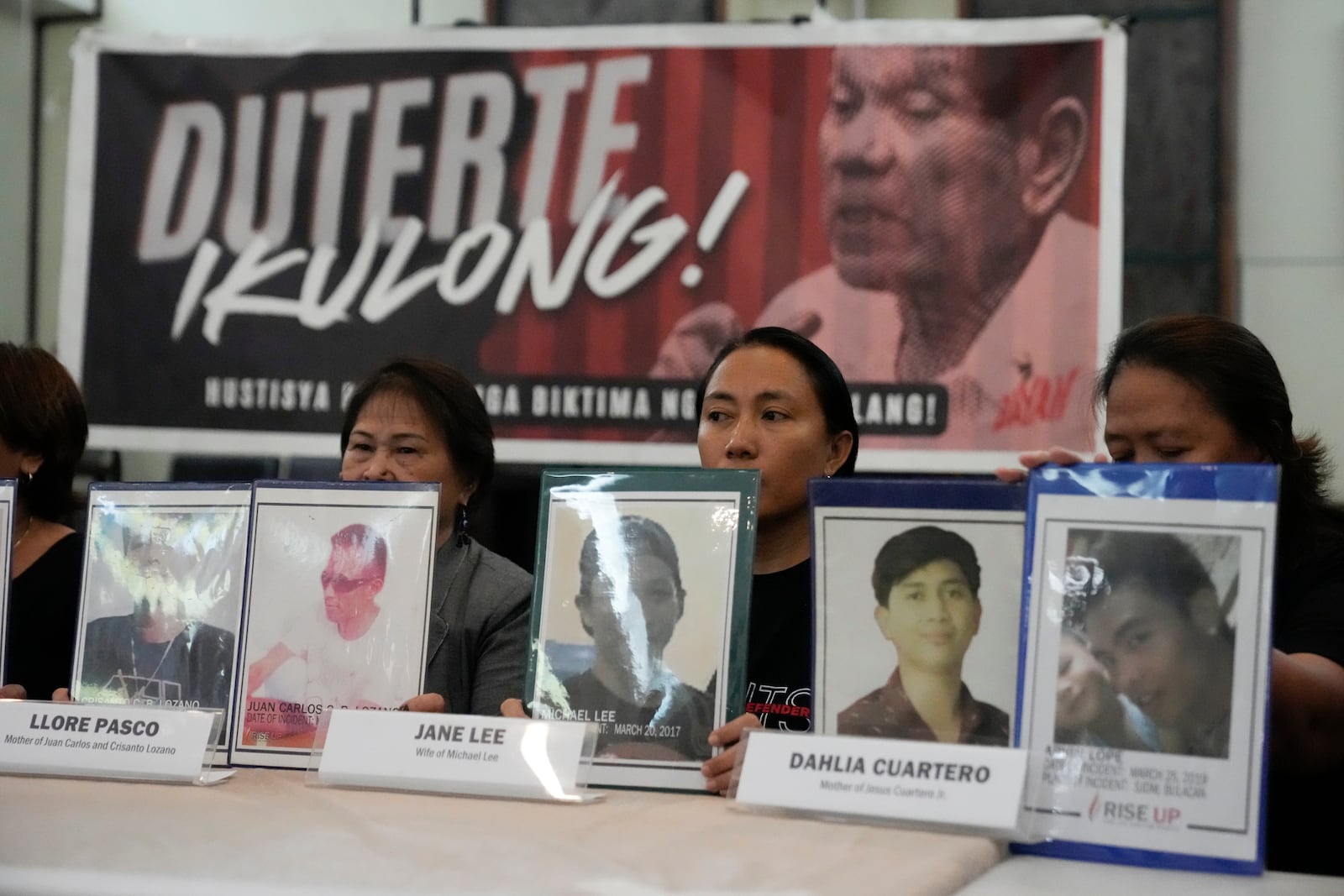 Relatives hold pictures of victims of alleged extra-judicial killings in front of a picture arrested former Philippine president Rodrigo Duterte with a sign that says "Jail Duterte" during a press conference in Quezon City, Philippines on Wednesday, March 12, 2025. (AP Photo/Aaron Favila)