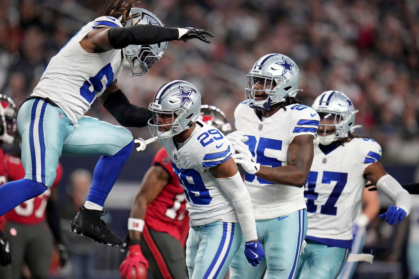 Dallas Cowboys' Buddy Johnson, left, and Andrew Booth Jr. (25) celebrate with C.J. Goodwin (29) after Goodwin made a stop on a punt coverage in the second half of an NFL football game against the Tampa Bay Buccaneers in Arlington, Texas, Sunday, Dec. 22, 2024. (AP Photo/Julio Cortez)