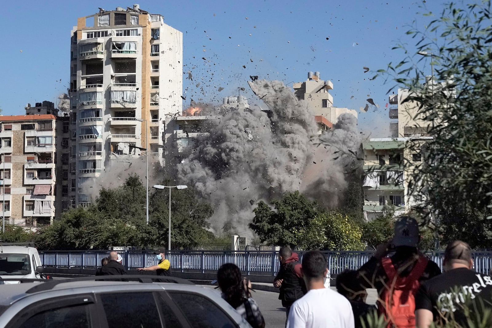 People watch a building collapse after being hit by an Israeli airstrike in Ghobeiri, Beirut, Lebanon, Tuesday, Oct. 22, 2024. (AP Photo/Bilal Hussein)