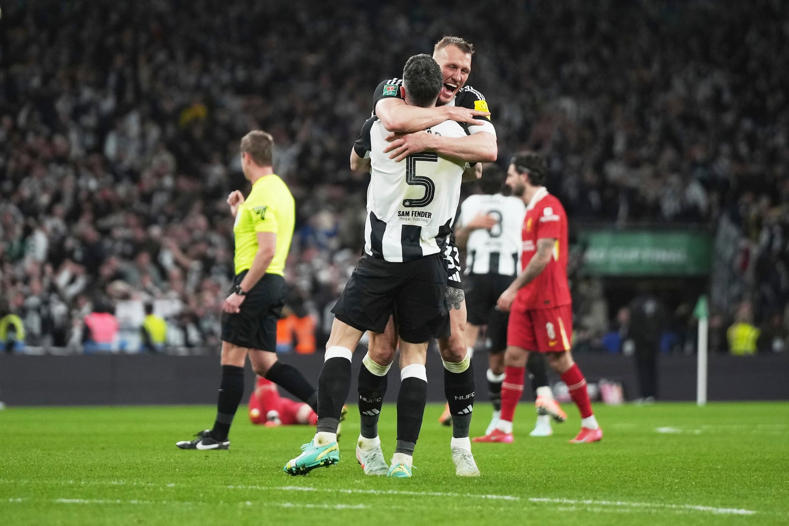 Newcastle's Dan Burn and Newcastle's Fabian Schaer celebrate after winning the EFL Cup final soccer match between Liverpool and Newcastle at Wembley Stadium in London, Sunday, March 16, 2025. (AP Photo/Alastair Grant)