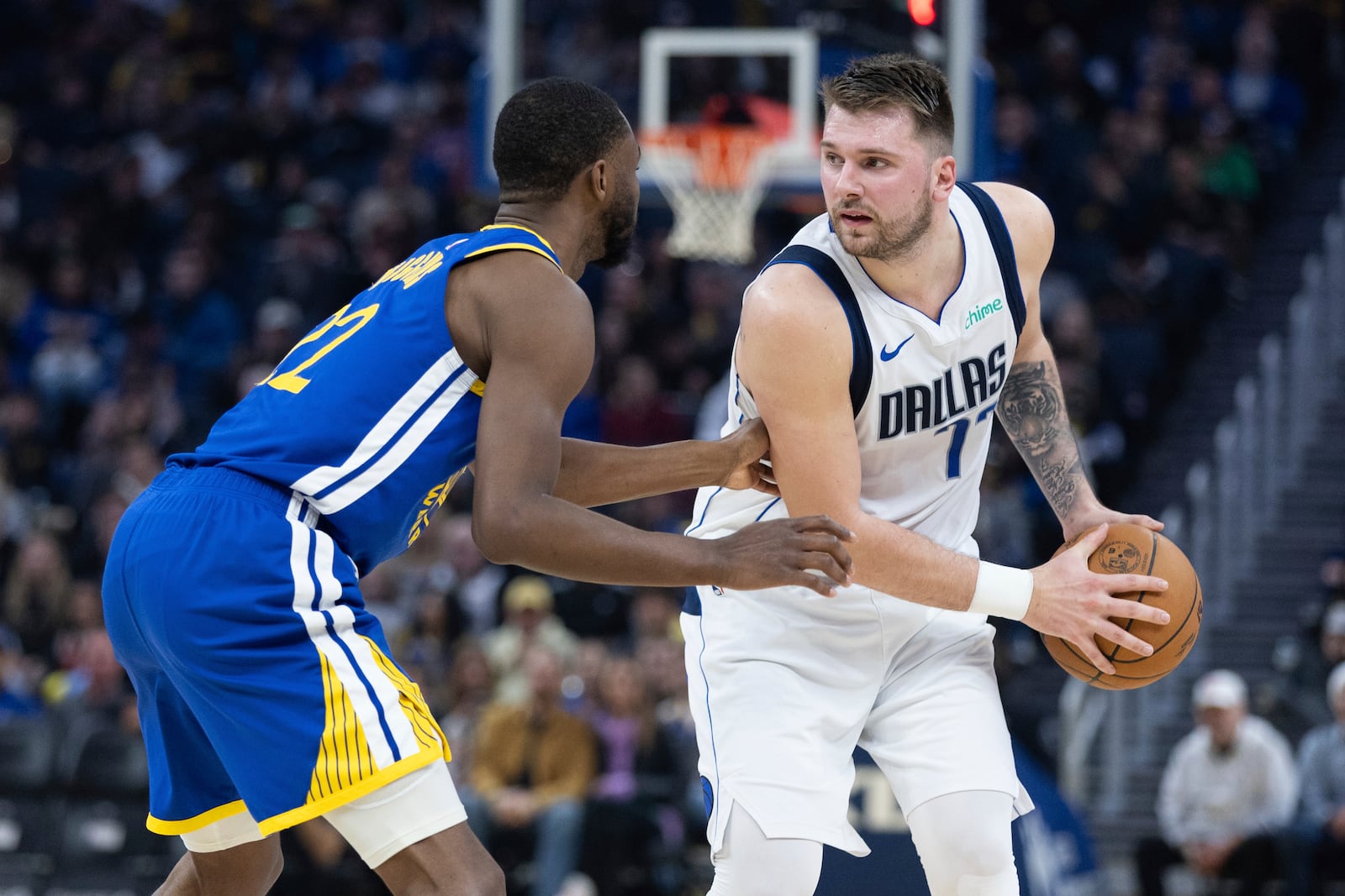 Golden State Warriors forward Andrew Wiggins, left, defends against Dallas Mavericks forward Luka Dončić, right, during the first half of an NBA basketball game Sunday, Dec. 15, 2024, in San Francisco. (AP Photo/Benjamin Fanjoy)