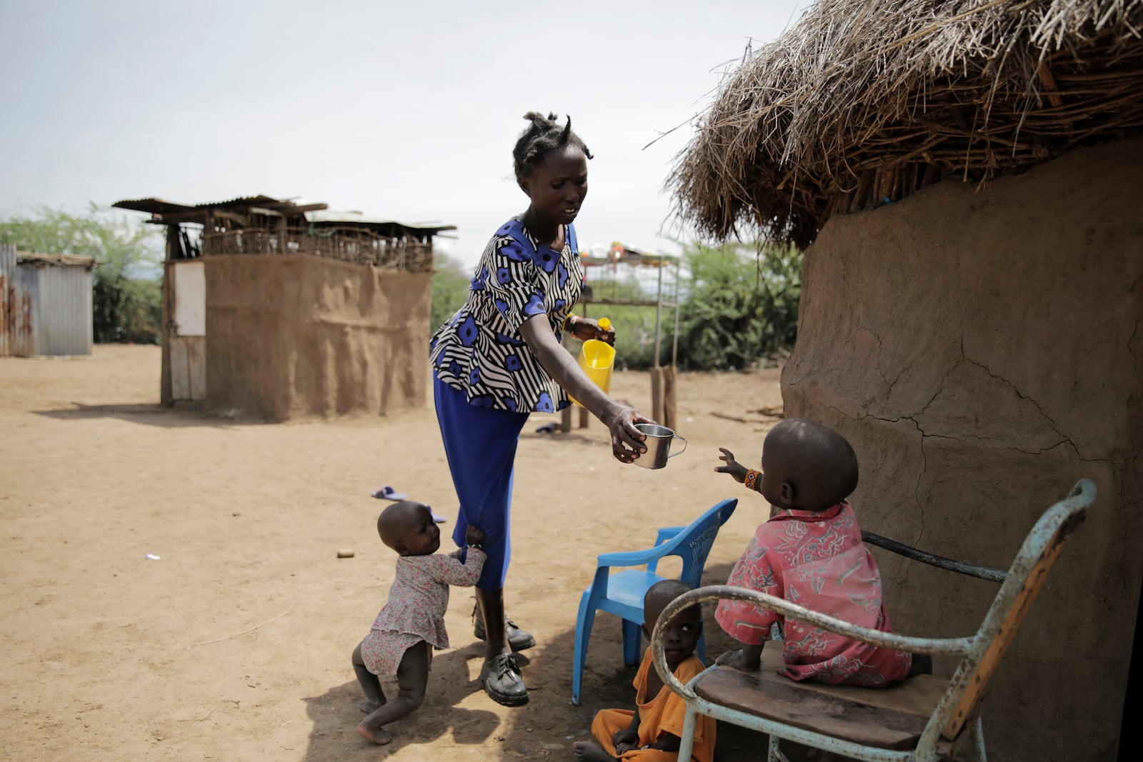 FILE - Winnie Keben gives water to her son at Meisori village in Baringo County, Kenya, July 20, 2022. Keben lost her leg to a crocodile attack, and that accident plus the loss of her home to rising water drove her and her family from their village. (AP Photo/Brian Inganga, File)