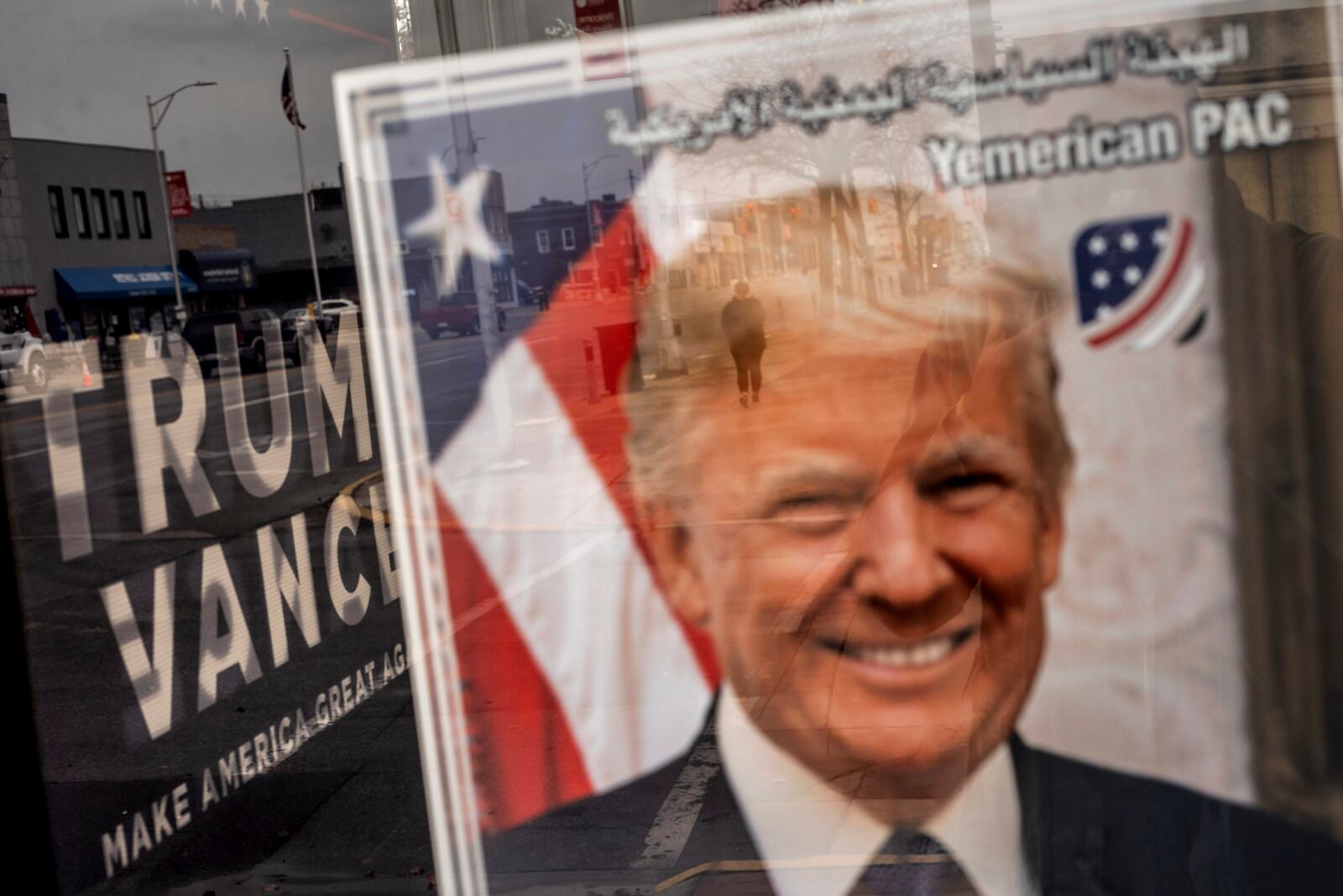 An image of Republican presidential nominee former President Donald Trump hangs in the window of a campaign office as a pedestrian passes by, Monday, Nov. 4, 2024, in Hamtramck, Mich. (AP Photo/David Goldman)