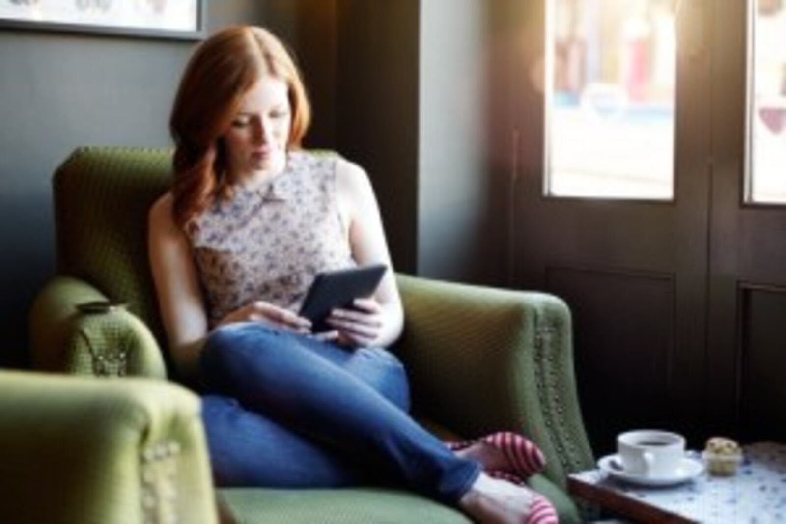 Woman reading ebook on tablet in coffee shop