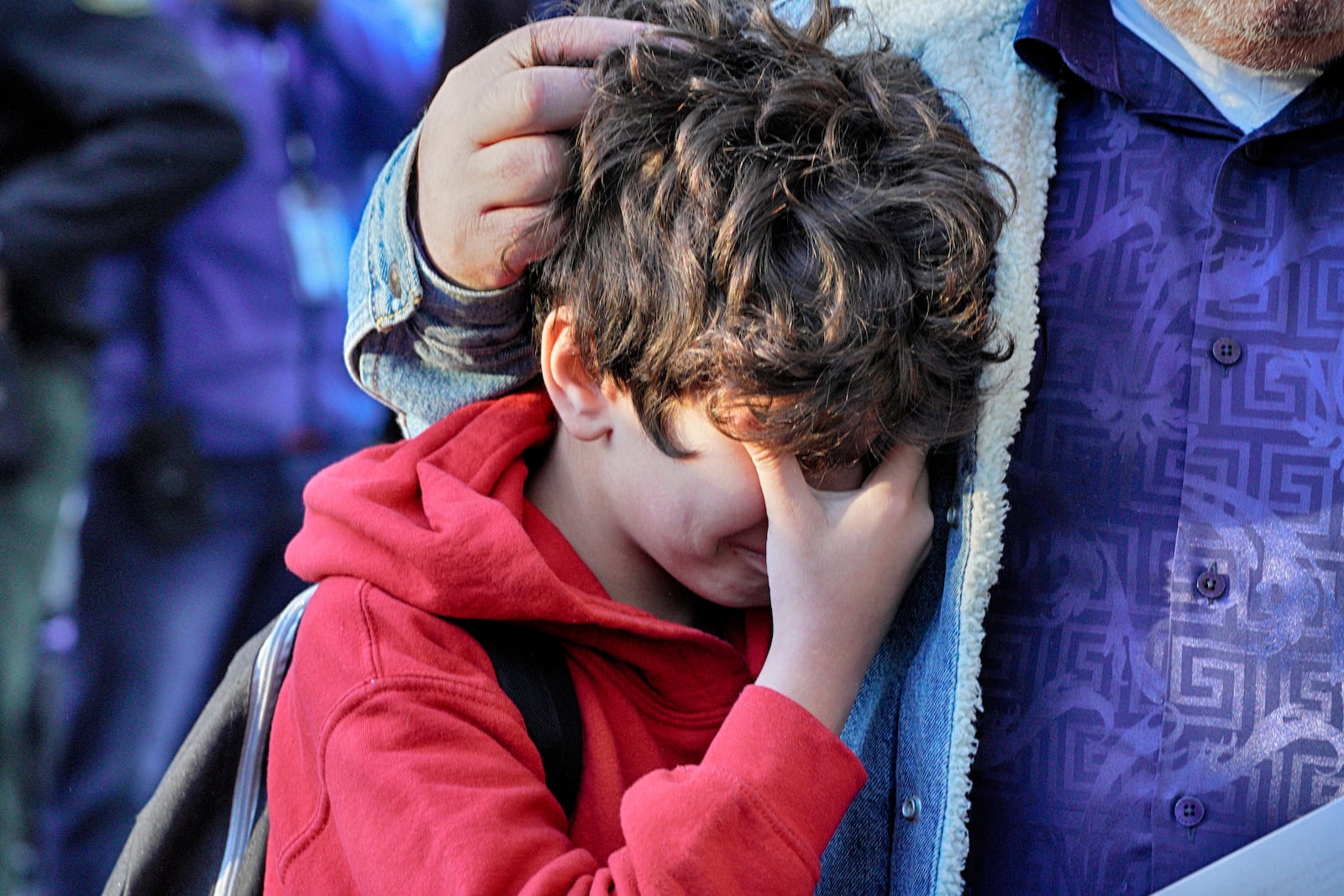 Palisades Charter Elementary School third grade student Jaden Koshki cries in his father's arm upon arriving at his new school, the Brentwood Elementary Science Magnet school in the Brentwood section of Los Angeles on Wednesday, Jan. 15, 2025. (AP Photo/Richard Vogel)