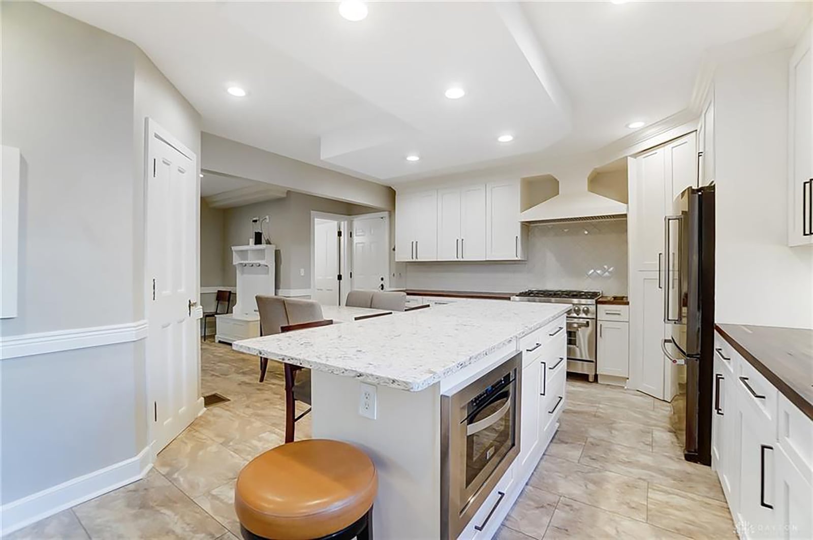 The updated kitchen has tile flooring, an island with granite countertops, tile backsplash and wood countertops on other surfaces and commercial grade appliances.