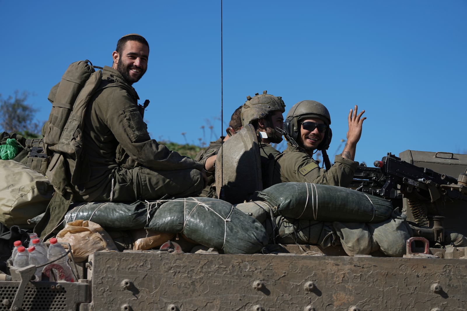 Israeli soldiers wave to the camera from an APC as they cross from the Gaza Strip into Israel, Saturday, Jan. 18, 2025. (AP Photo/Tsafrir Abayov)