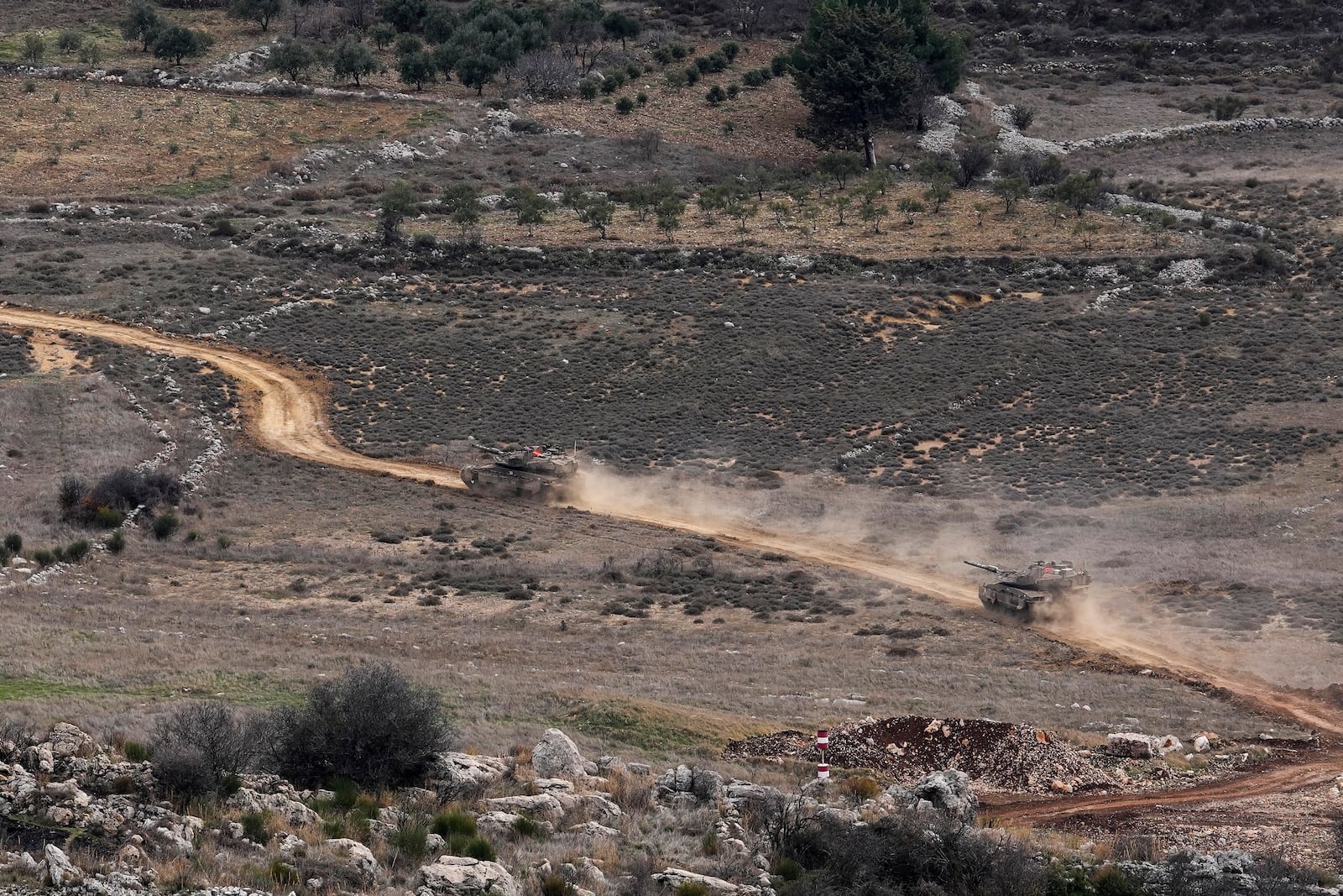 Israeli tanks cross the security fence moving towards the so-called Alpha Line that separates the Israeli-annexed Golan Heights from Syria, in the town of Majdal Shams, Wednesday, Dec. 11, 2024. (AP Photo/Matias Delacroix)