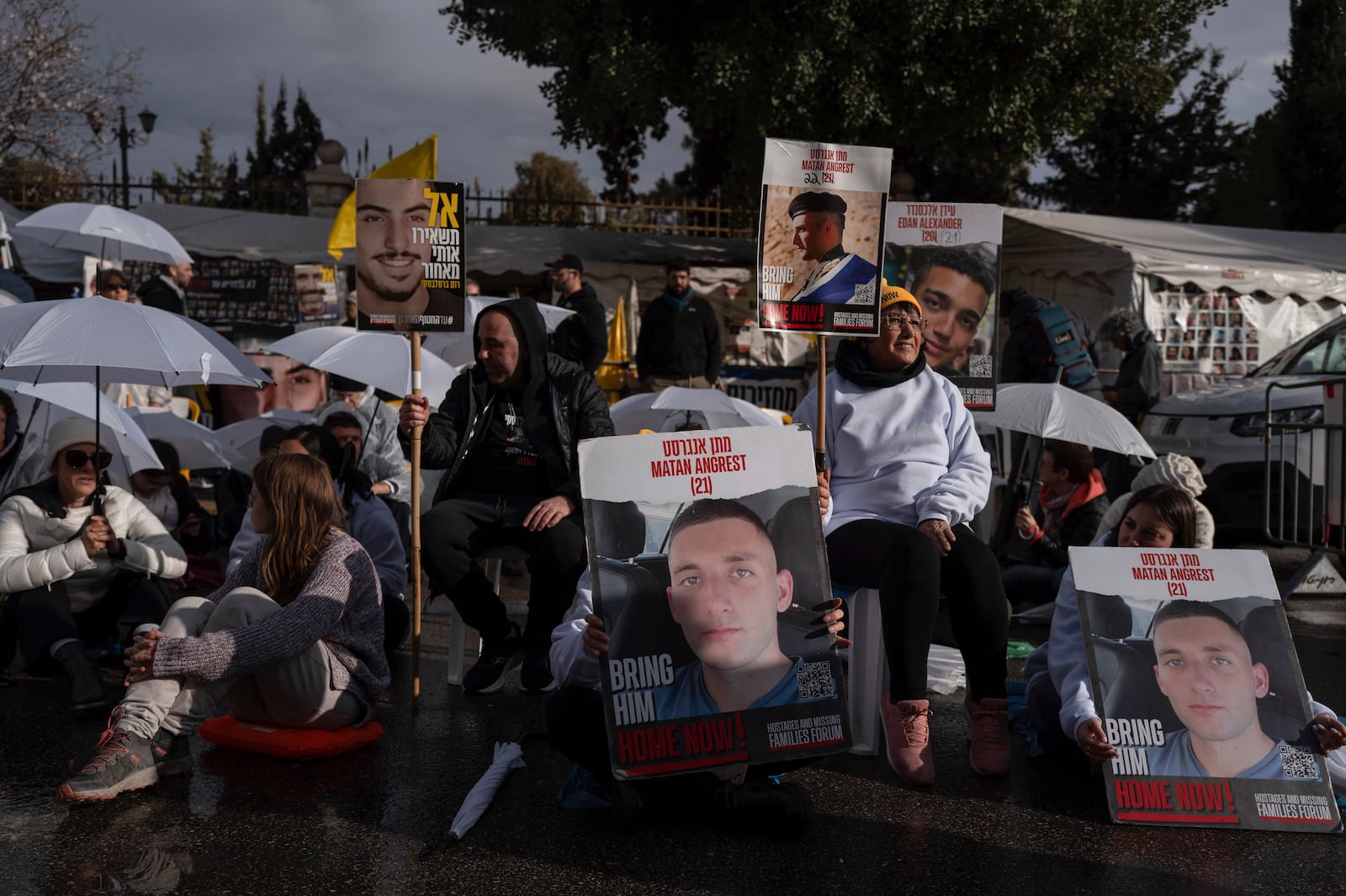 Activists sit on a road with white umbrellas during a protest calling for the release of hostages held in the Gaza Strip, outside the prime minister's house in Jerusalem, Wednesday, Feb. 12, 2025. (AP Photo/Ohad Zwigenberg)