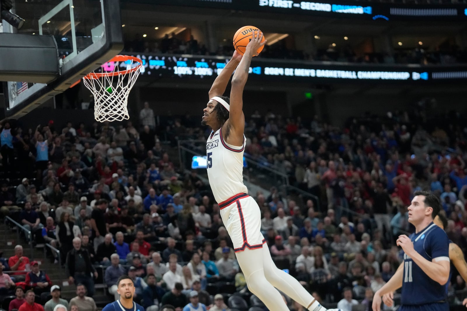 Nevada forward Nick Davidson (11) watches as Dayton forward DaRon Holmes II, top center, dunks during the first half of a first-round college basketball game in the NCAA Tournament in Salt Lake City, Thursday, March 21, 2024. (AP Photo/Rick Bowmer)