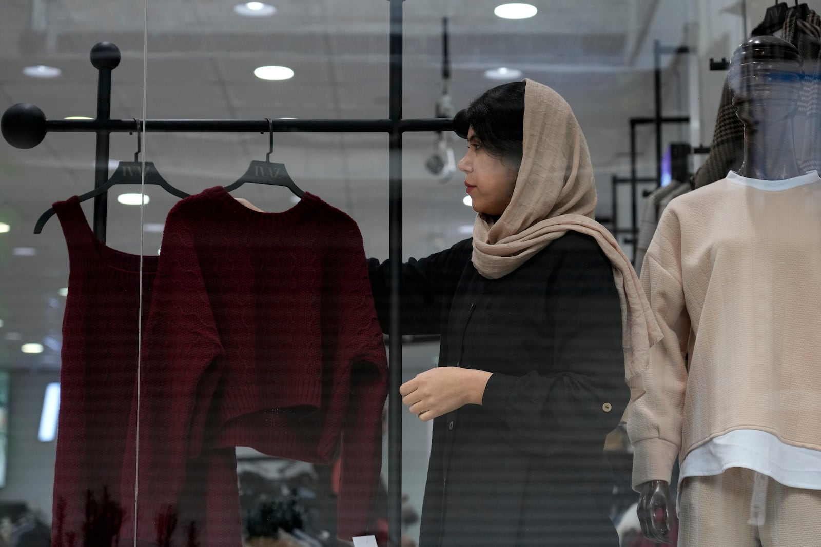 A shopkeeper puts on a woman's clothes on a mannequin at a shop in port city of Bandar Anzali in northern Iran, Thursday, Dec. 5, 2024. (AP Photo/Vahid Salemi)