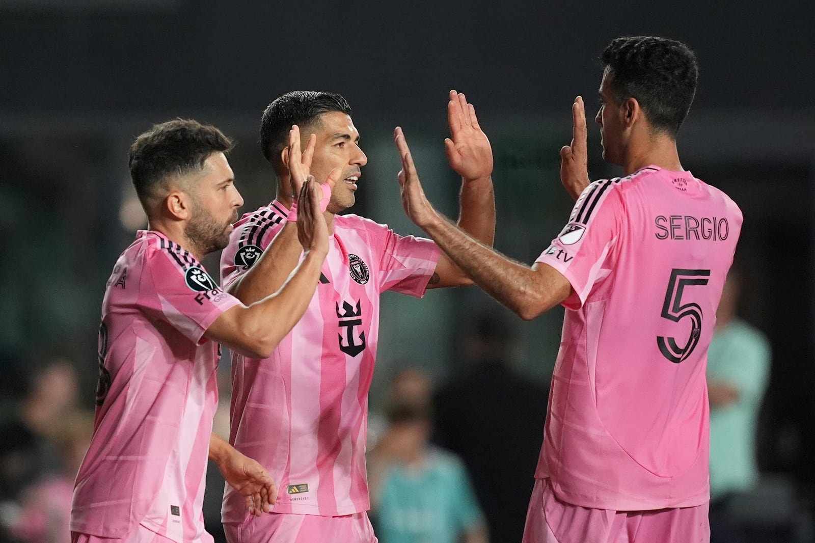 Inter Miami forward Luis Suarez, center, celebrates with teammates defender Jordi Alba, left, and midfielder Sergio Busquets (5) after scoring his side's third goal against Sporting Kansas City, during the first half of a CONCACAF Champions Cup soccer match, Tuesday, Feb. 25, 2025, in Fort Lauderdale, Fla. (AP Photo/Rebecca Blackwell)