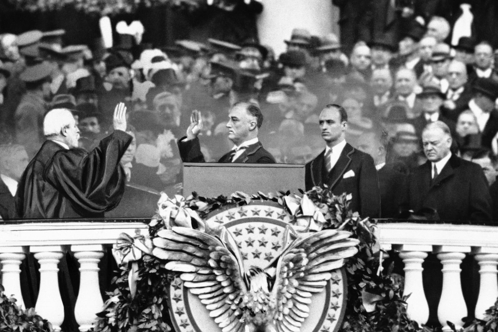 FILE - Outgoing President Herbert Hoover, right, gazes downward as President-elect Franklin D. Roosevelt, accompanied by his eldest son James, takes the oath of office from Chief Justice Charles E. Hughes, in Washington, March 4, 1933. (AP Photo, File)