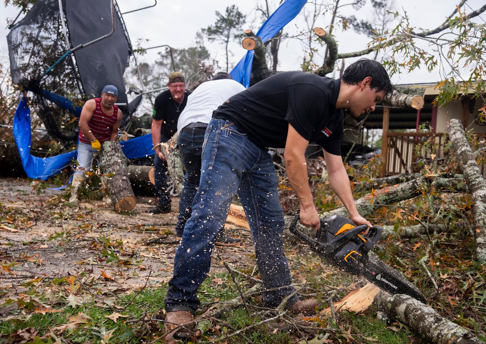 Ricardo Rodriguez uses a chain saw to remove debris from a woman's home after strong thunderstorms pass through the Greater Houston region, Saturday, Dec. 28, 2024, in Porter Heights. (Jason Fochtman/Houston Chronicle via AP)