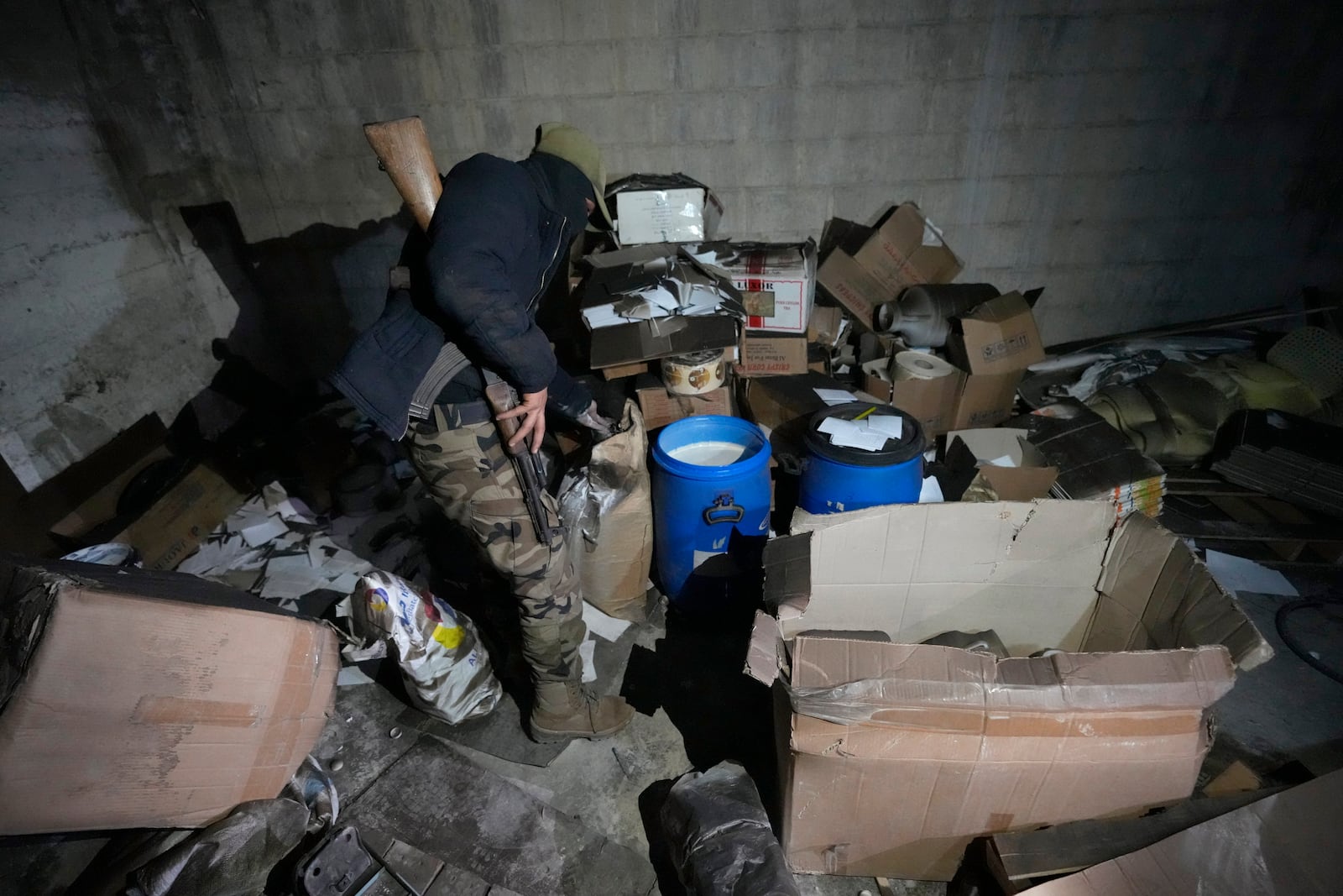 A Syrian member of the rebel group inspect material for manufacturing amphetamine pills, known as Captagon, hidden at the warehouse where the drug was manufactured before the fall of Bashar Assad government at a facility in Douma city, outskirts of Damascus, Syria, Friday, Dec. 13, 2024. (AP Photo/Hussein Malla)