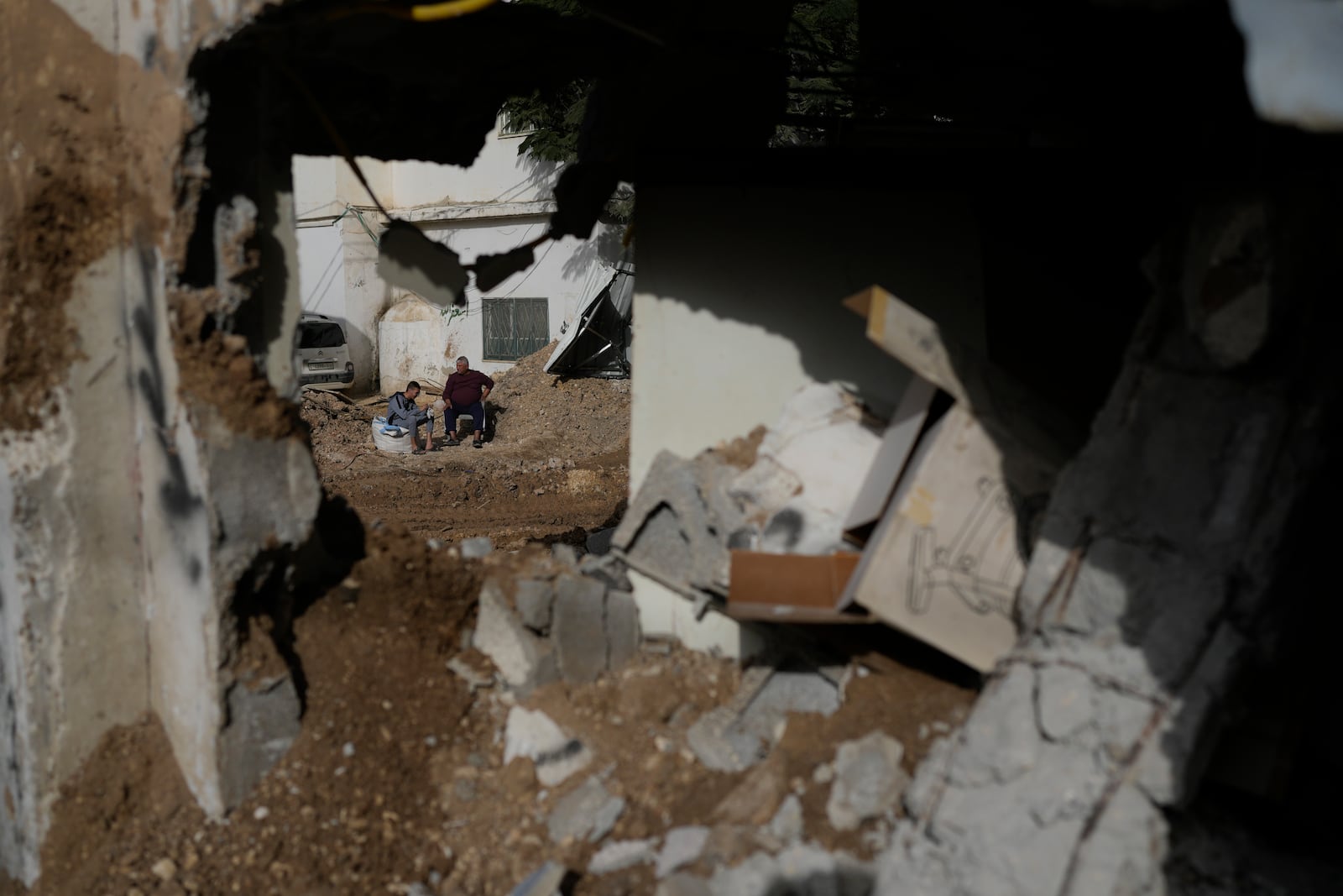 Locals stand next to a damaged building after the latest Israeli military operation, in the West Bank city of Tulkarem, Thursday, Dec. 26, 2024. (AP Photo/Matias Delacroix)