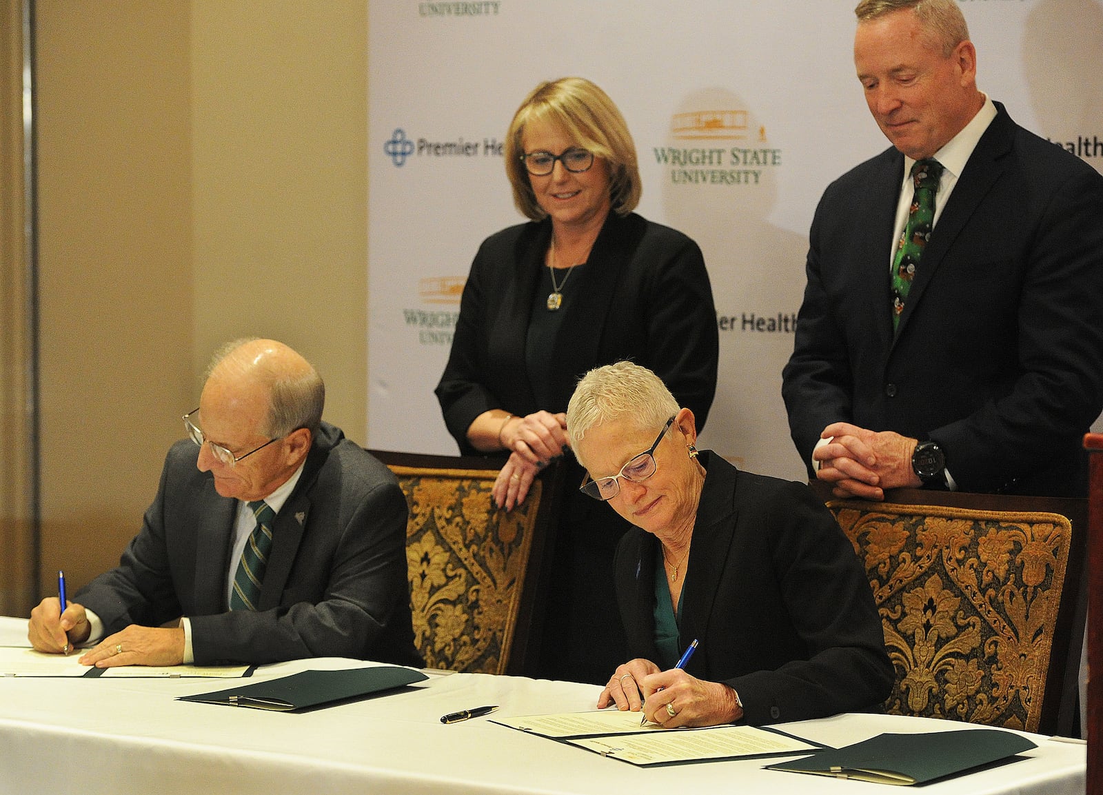 Tom Gunlock, chair of the Wright State University Board of Trustees, and Kathleen Carlson, chair of the Premier Health Board of Trustees, signed an expanded affiliation agreement on Friday, Dec. 15, 2023. They were joined by Sue Edwards, president of Wright State University, and Michael C. Riordan, president and CEO of Premier Health. MARSHALL GORBY\STAFF