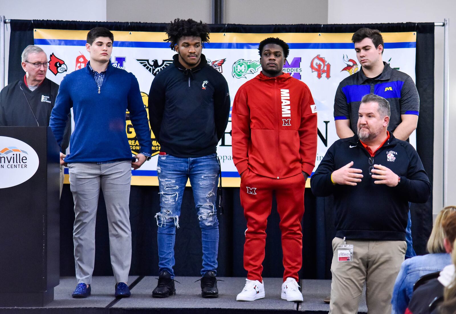 Lakota West football coach Tom Bolden, front right, introduces his players during the Greater Miami Conference football signing day program Wednesday, Feb. 5 at Sharonville Convention Center. Left to right: Isaac signed with Butler University, Daved Jones signed with University of Cincinnati, David Afari signed with Miami University, and Jake Kieffer signed with Morehead State University. Over fifty students from the ten schools in the league have signed letters of intent to play football in college. NICK GRAHAM / STAFF