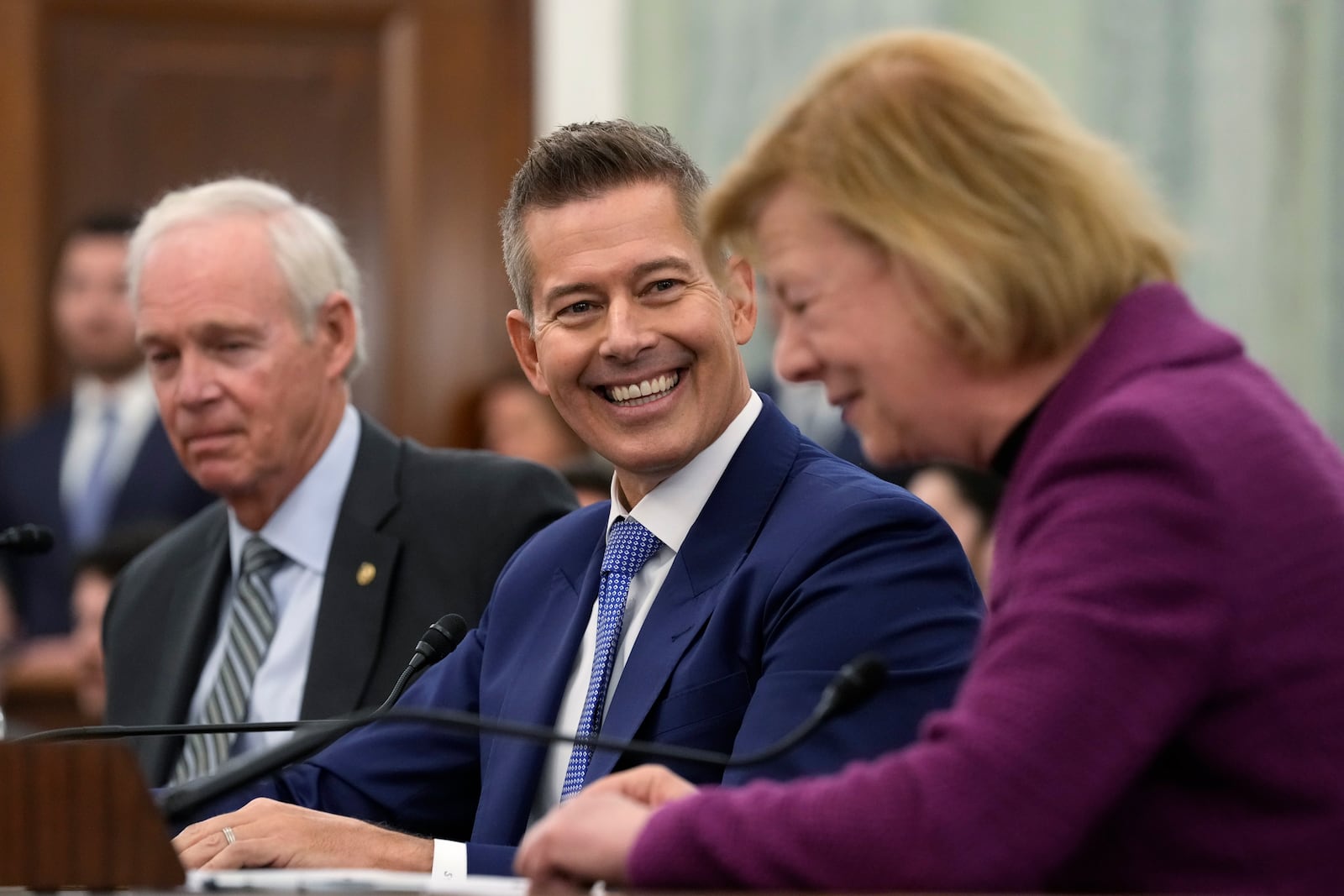 Former Wisconsin Rep. Sean Duffy, R-Wis., center, smiles as Sen. Tammy Baldwin, D-Wis., right, introduces him before he testifies before the Senate Commerce, Science, and Transportation Committee on Capitol Hill in Washington, Wednesday, Jan. 15, 2025, to be Transportation Secretary. Sen. Ron Johnson, R-Wis., left, also introduced Duffy. (AP Photo/Susan Walsh)