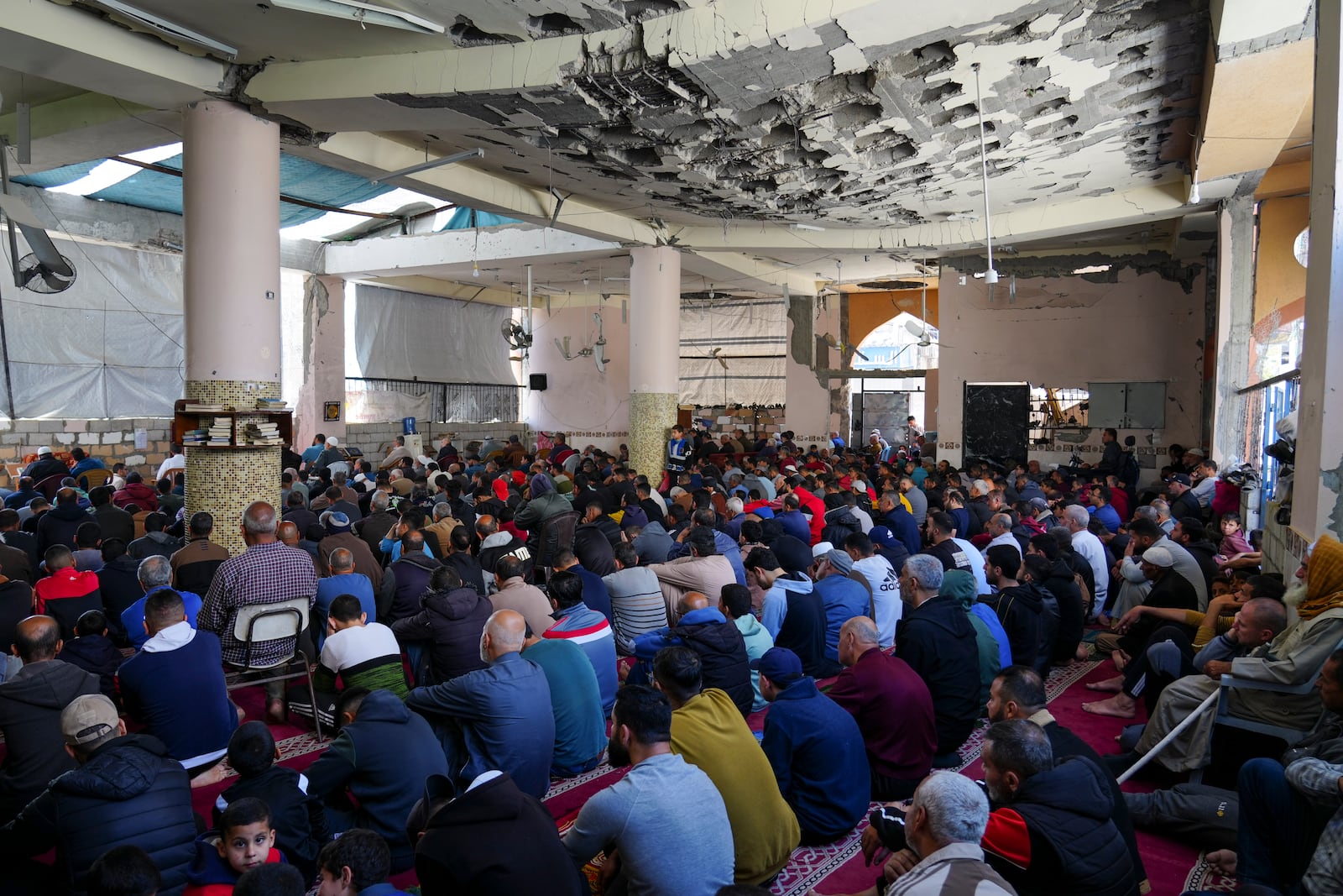 Palestinians take part in Friday prayers in the ruins of a Mosque that was partially destroyed by Israeli bombardment, in Nuseirat, Gaza Strip, Friday, March 14, 2025, during the holy Muslim month of Ramadan. (AP Photo/Abdel Kareem Hana)