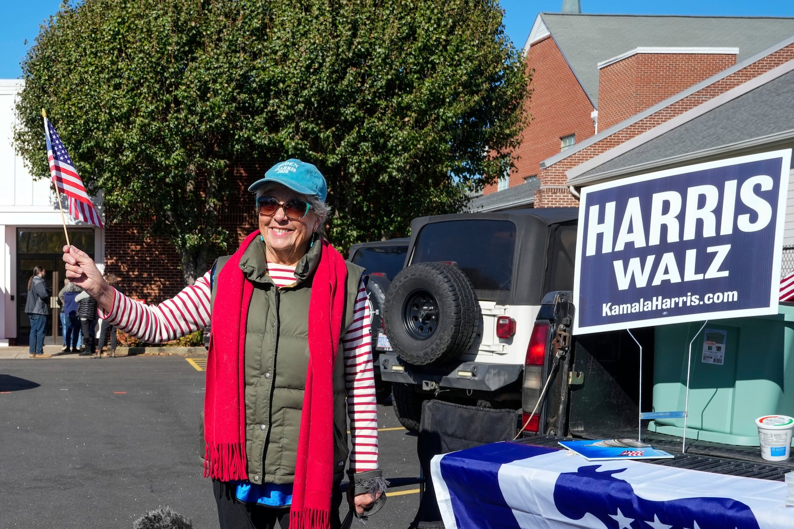 Outside the Rutherford County Annex Building where early voting is taking place, Susan McGowan waves a United States flag in support of Vice President Kamala Harris and Governor Tim Walz, Thursday, October 17, 2024 in Rutherfordton, N.C. (AP Photo/Kathy Kmonicek)