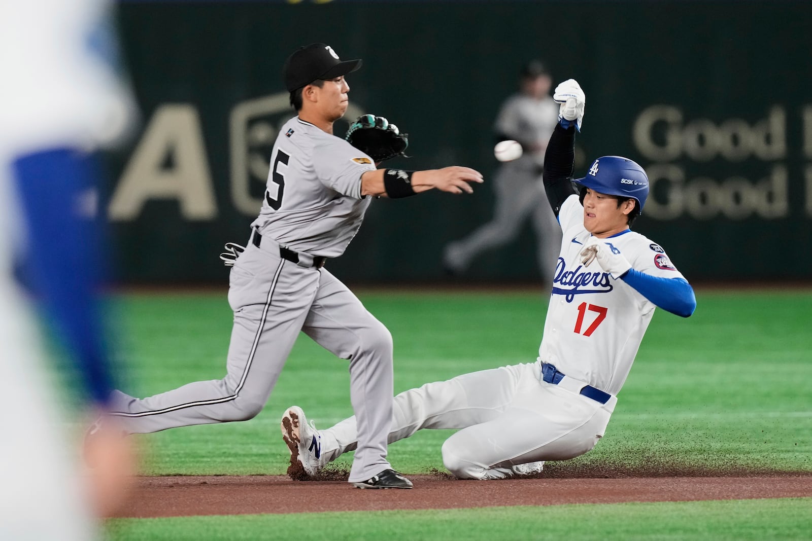 Yomiuri Giants' Makoto Kadowaki, left, throws to first to complete the double play after forcing Los Angeles Dodgers' Shohei Ohtani, right, at second in the first inning of a spring training baseball game in Tokyo, Japan, Saturday, March 15, 2025. (AP Photo/Eugene Hoshiko)