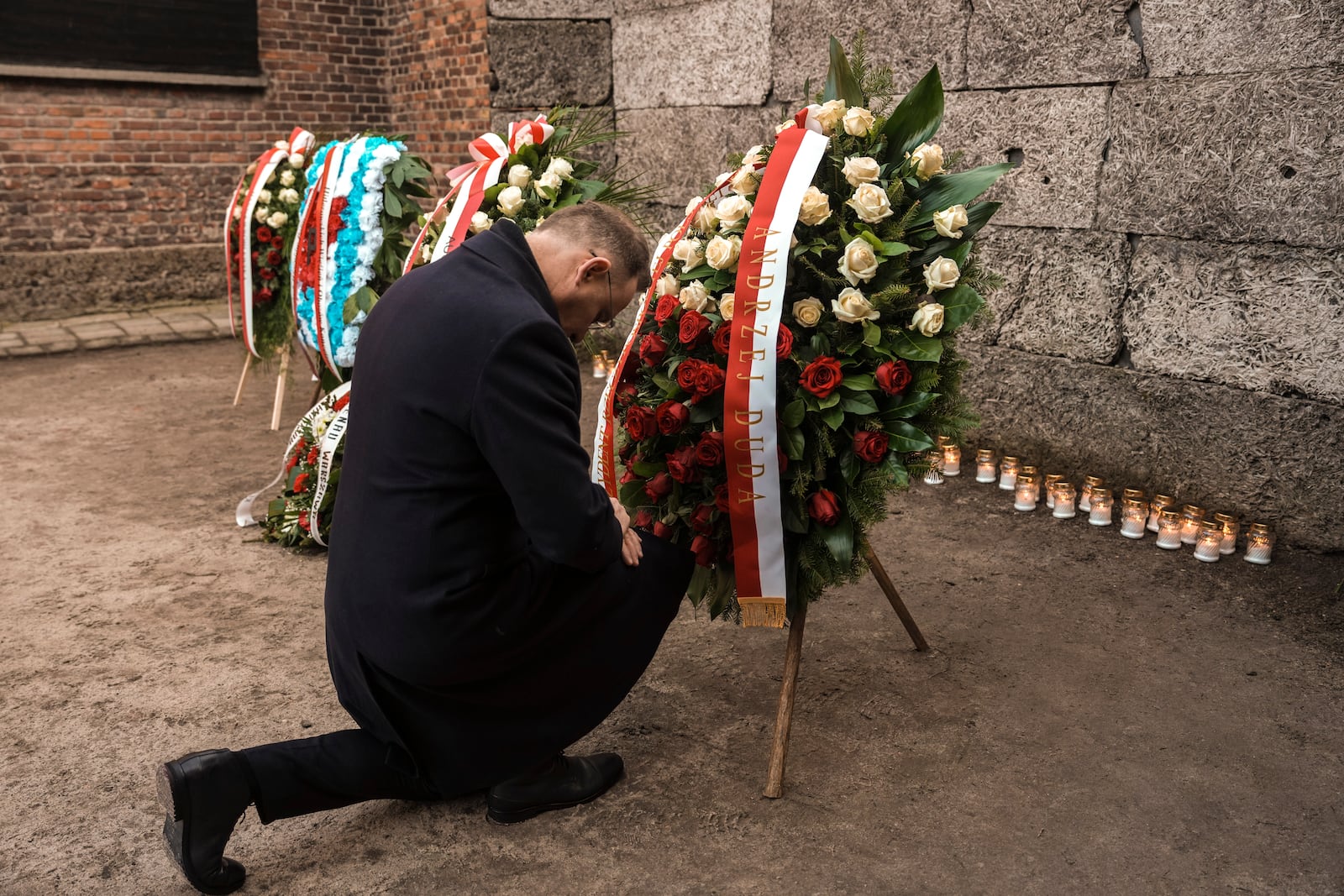 Polish President Andrzej Duda kneels in front of the Death Wall at the Auschwitz-Birkenau former Nazi German concentration and extermination camp, during a ceremony in Oswiecim, Poland, Monday, Jan. 27. 2025. (AP Photo/Oded Balilty)