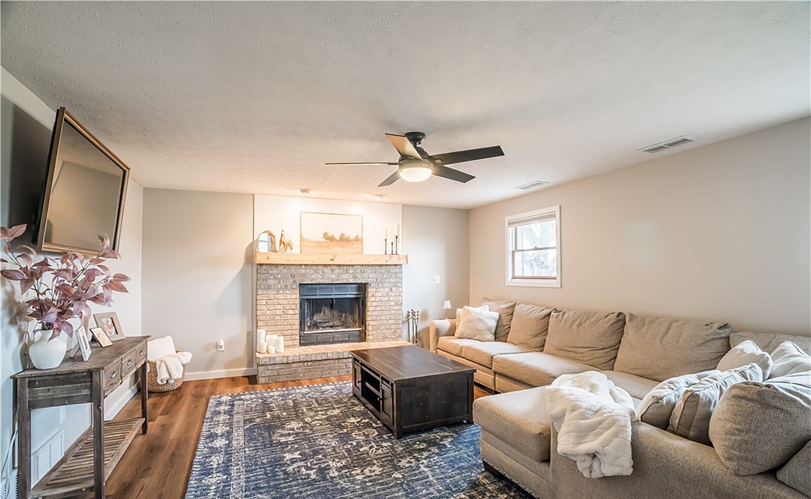 The lower level family room has a brick woodburning fireplace, luxury vinyl tile flooring and recessed lighting.